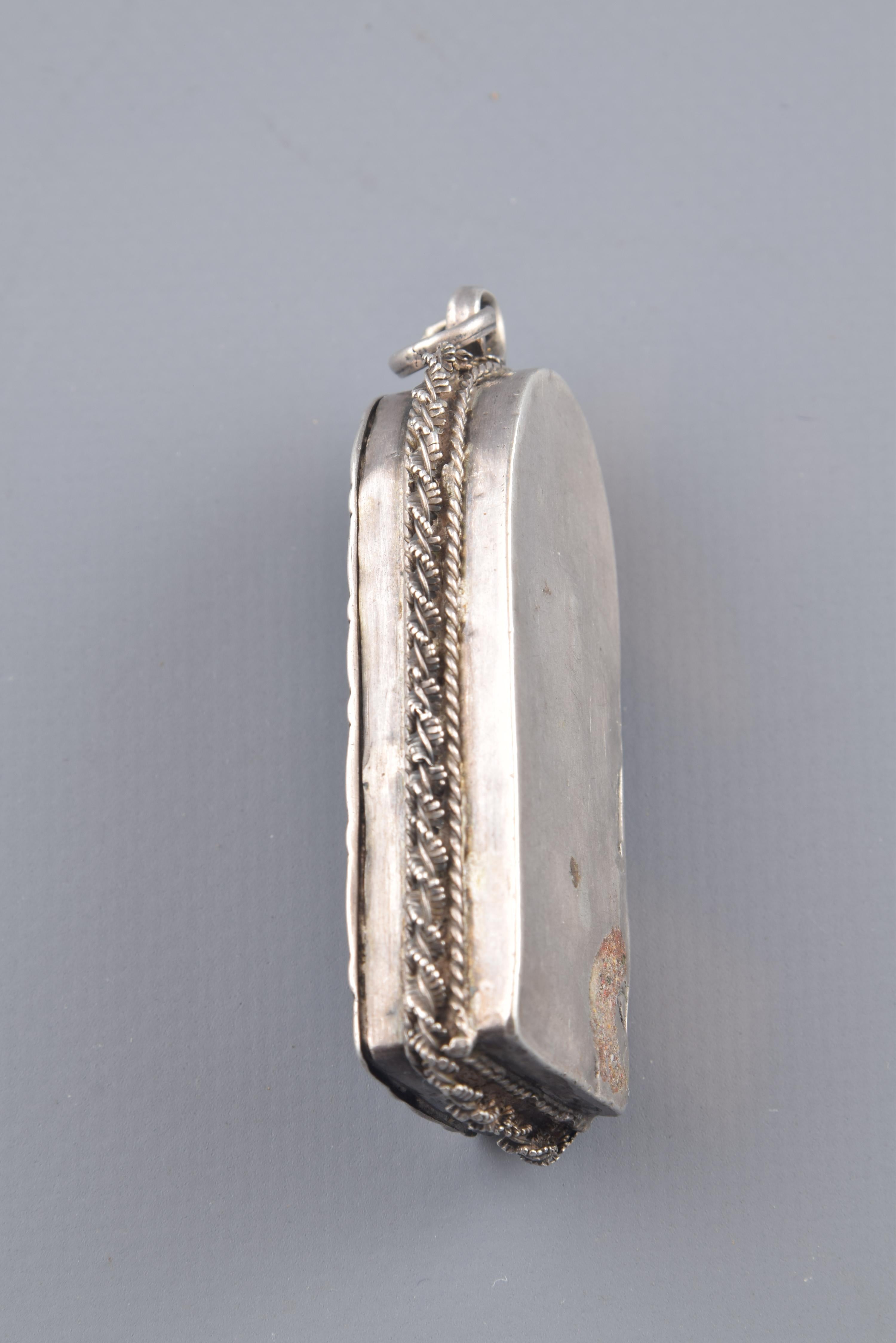 A devotional pendant in the shape of a chapel or altar, rectangular rectangular topped by a semicircle on which the piece that allows hanging the jewel is placed. On the outside, it has been decorated with a series of engraved lines and with some