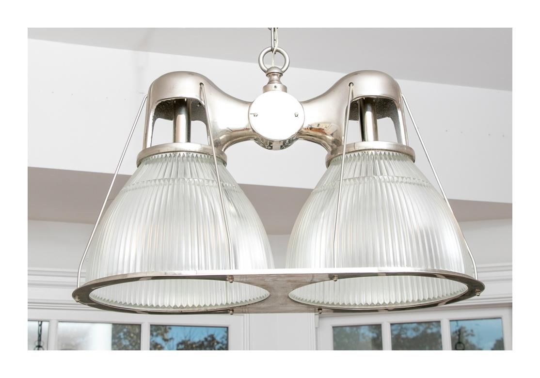 Solid Industrial style in a Double Light Hanging Fixture. A fixture from Remains Antique Lighting, NYC, Holophane double pendant lamp with ribbed glass shades and an industrial flair. 
Dimensions: 30 1/2