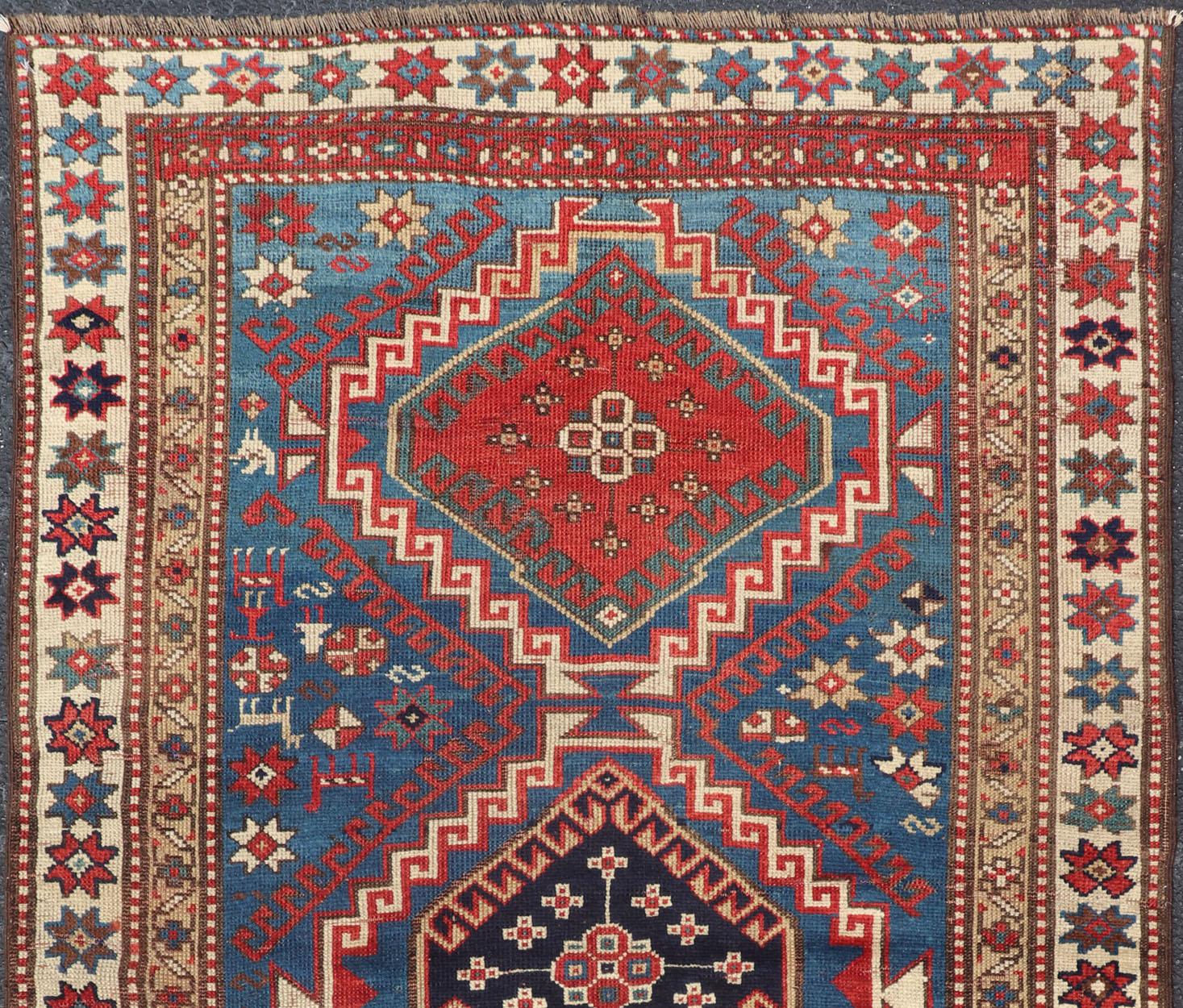 Tribal geometric medallion design Kazak antique rug, antique Caucasian from Caucasus Region with a beautiful blue background in multi-colors. Keivan Woven Arts /  rug 19-0601, country of origin / type: Caucuses / Caucasian Kazak, circa