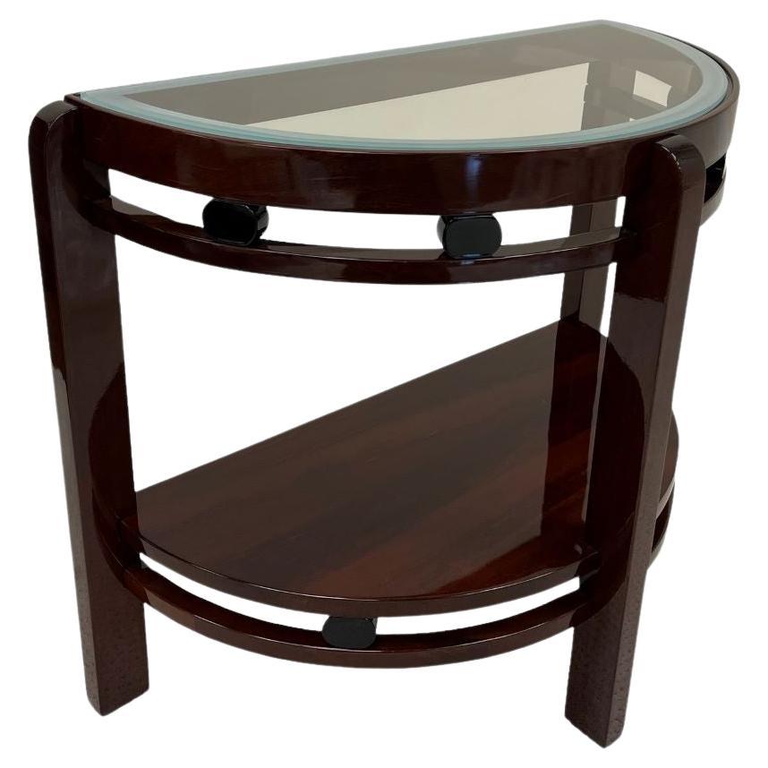     A stunning Art Deco half circle side table circa American 1930’s. Expertly crafted maple stained mahogany with black lacquered oval accents and a beautifully sandblasted edge glass top. An elegant and dramatic example from the American Machine