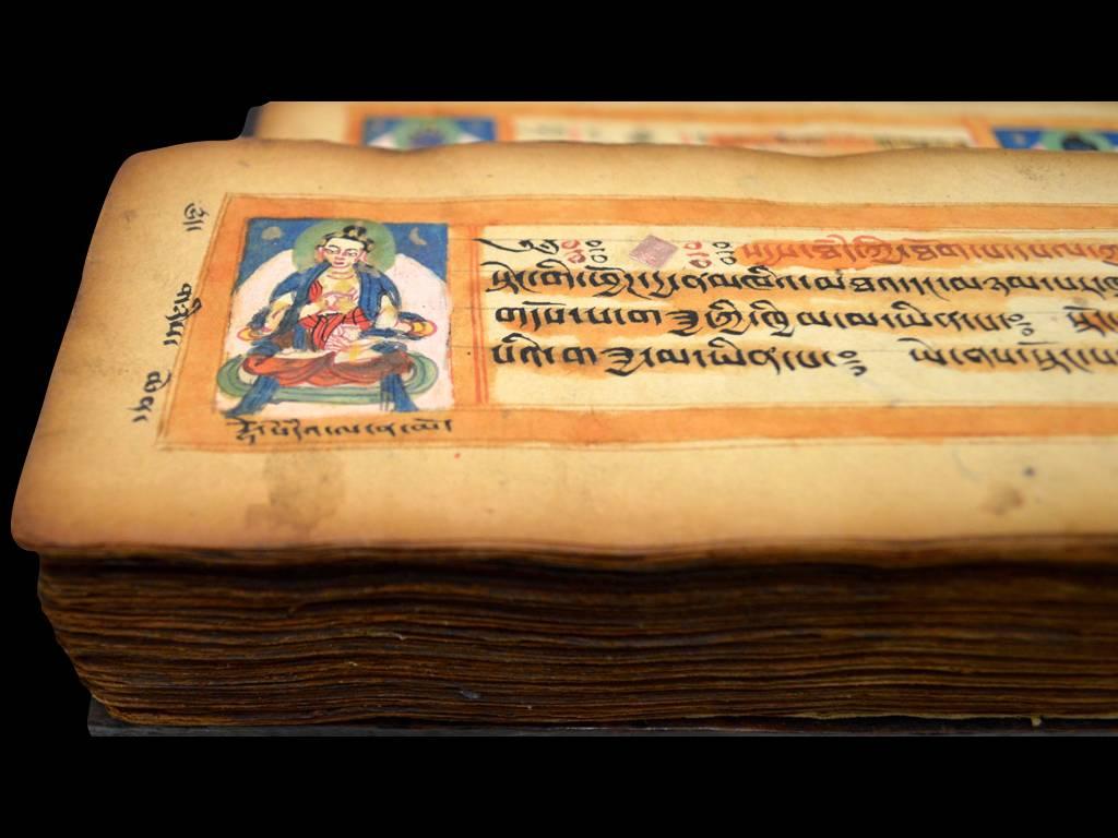 Magnificent hand-written Tibetan manuscript sutra with pictures of deites in the first three pages. It is accompanied by dense hard redwood covers, the top cover is decorated with geometrical lines. The top side and the edges show a black thick