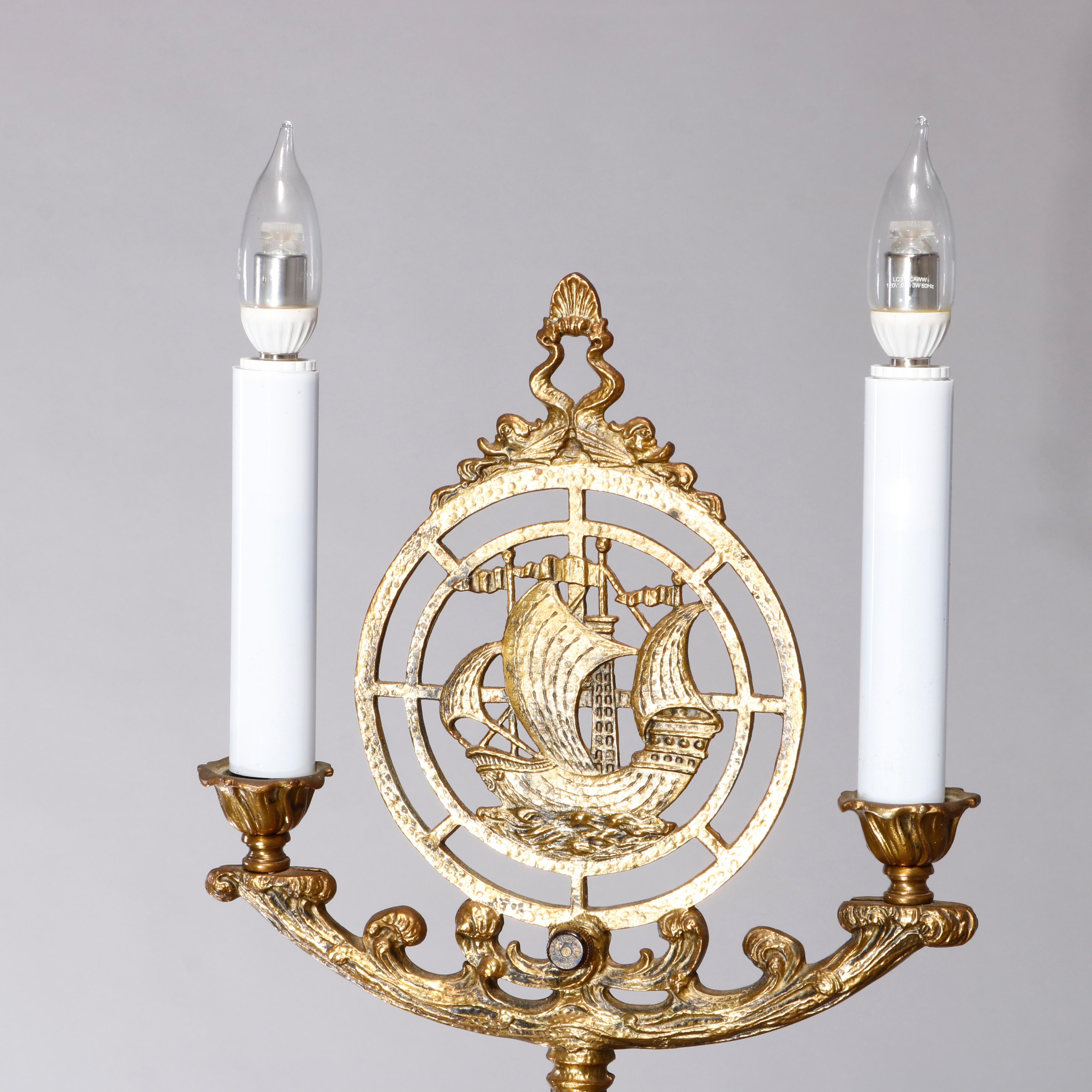 An antique floor lamp in the manner of Rembrandt offers wrought iron and brass construction with Maritime elements including tall mast ships and sea serpents with double candle lights, circa 1920.

Measures: 65.5