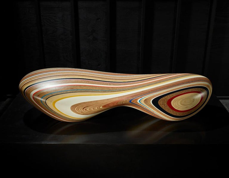 The multicolored Remix is an organically shaped, low chaise longue carved from reclaimed and sourced materials including a mixture of plastics and woods. The randomly selected mix of materials is laminated into a block, which is contoured by a