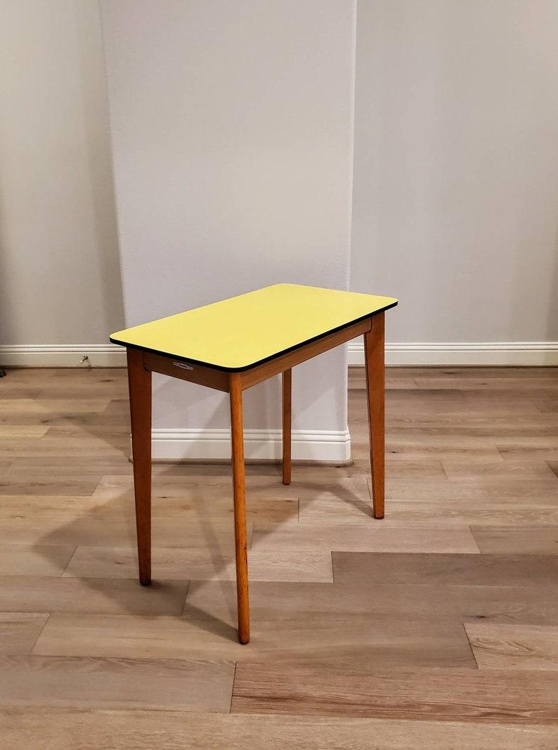 A fabulously retro English modern side table by iconic UK designer Remploy. Born in midcentury England, Parson table form, two tone, having a rectangular top with bright yellow formica top and ebonized rim, over solid teak wood frame, rising on four
