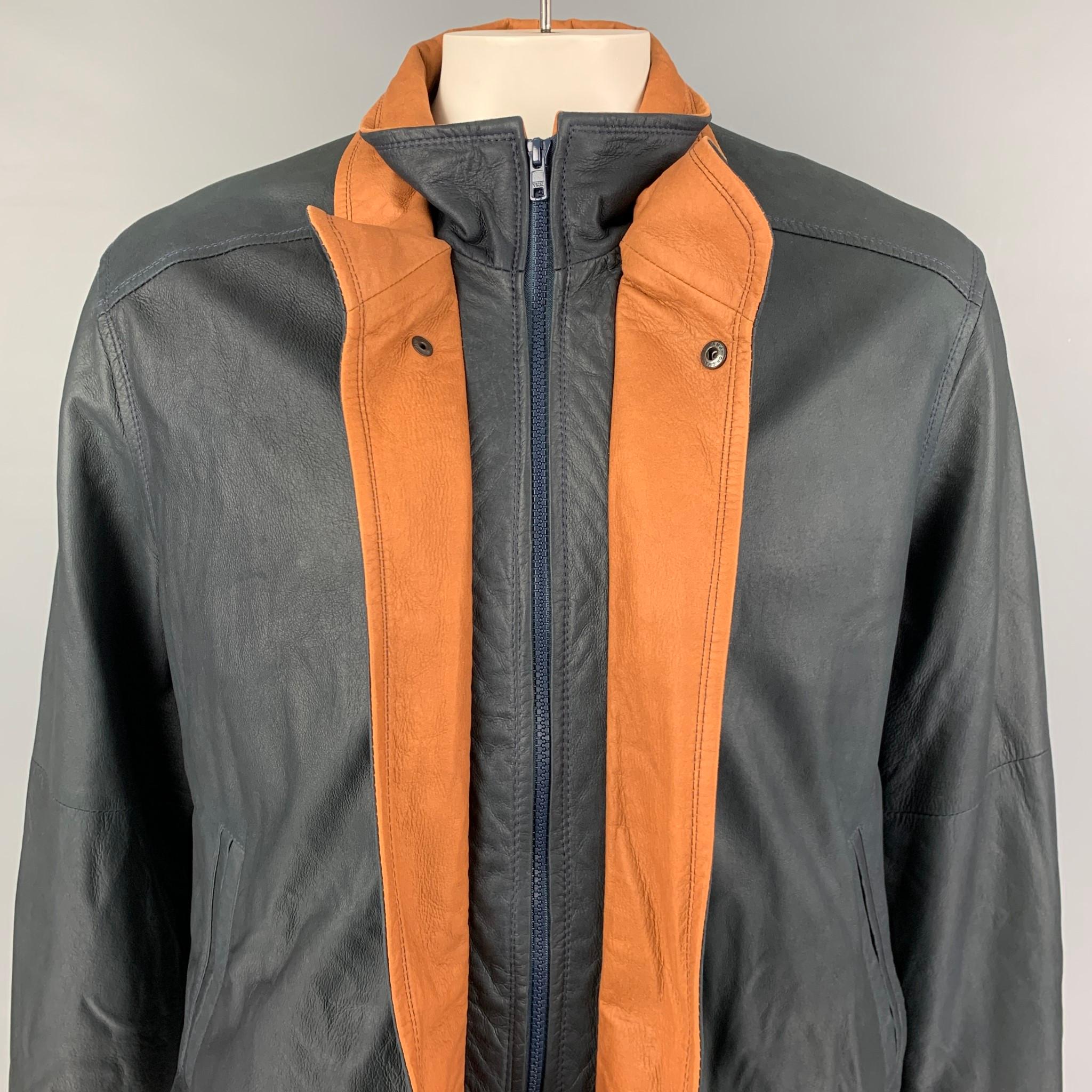 REMY jacket comes in a navy & tan leather featuring a high collar, contrasting trim, slit pockets, and a full zip up closure. Made in USA. 

Very Good Pre-Owned Condition.
Marked: 42

Measurements:

Shoulder: 20 in.
Chest: 48 in.
Sleeve: 27.5