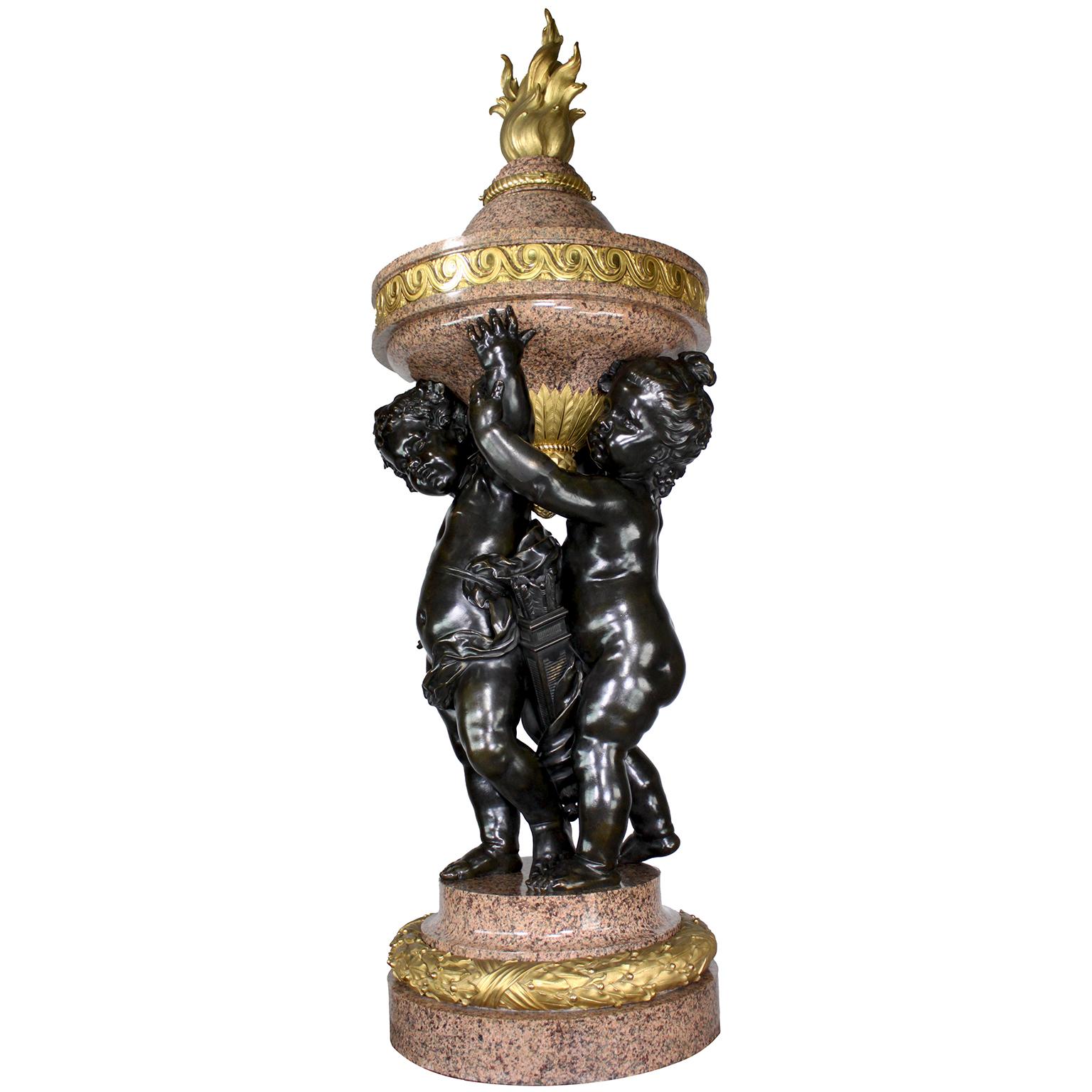 A Monumental Museum Quality Pair of French 19th Century Figural Gilt and Patinated Bronze Rosso Granite Marble Flambeaux Urns, each depicting a pair of standing allegorical and whimsical playful children (Putti) holding a flaming urn, by René Rozet