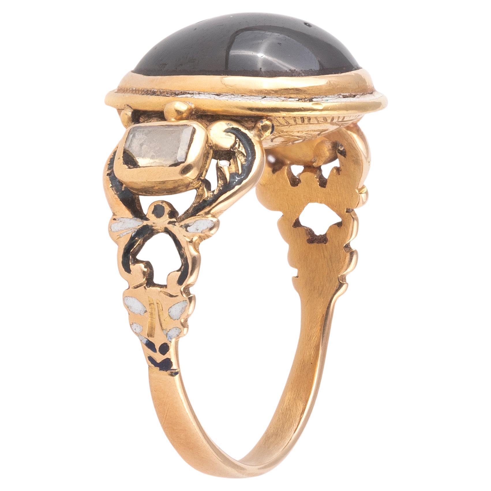 This elegant ring is typical of the Renaissance, with its elaborate design that combines a gemstone in a high bezel, sculptural elements and table cut diamonds at the shoulders and colorful enamels. 

Gold, garnet, table cut diamond and