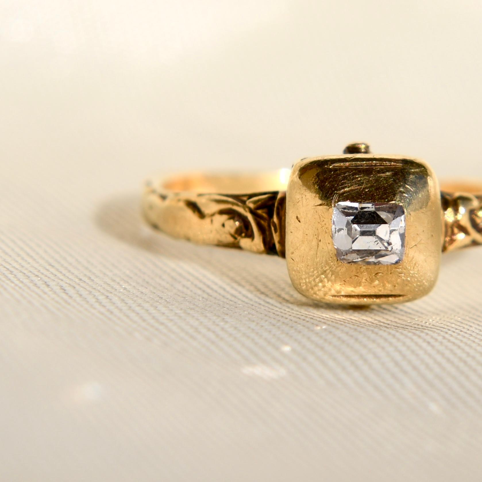 An elegant, high carat, yellow gold Renaissance ring with a table-cut diamond in a rounded box setting with at the back a hatched border and vestigial four-claw setting decorated with black enamel, with a round hoop florally engraved from the