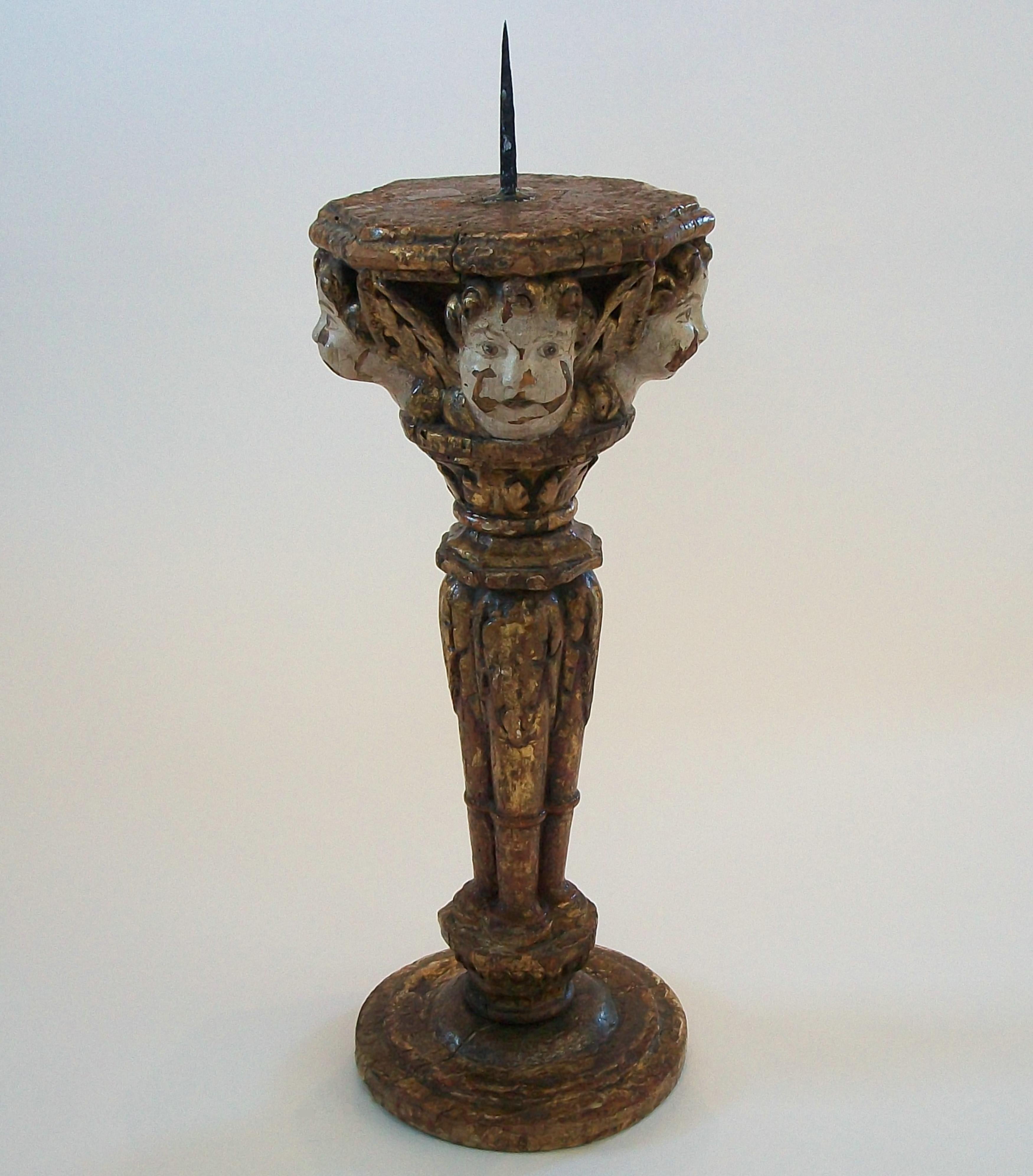 Renaissance period painted and giltwood candle holder or pricket - featuring four elaborately hand carved winged cherubs beneath an octogonal platform with the original hand forged iron pricket, all resting on a column consisting of four upright