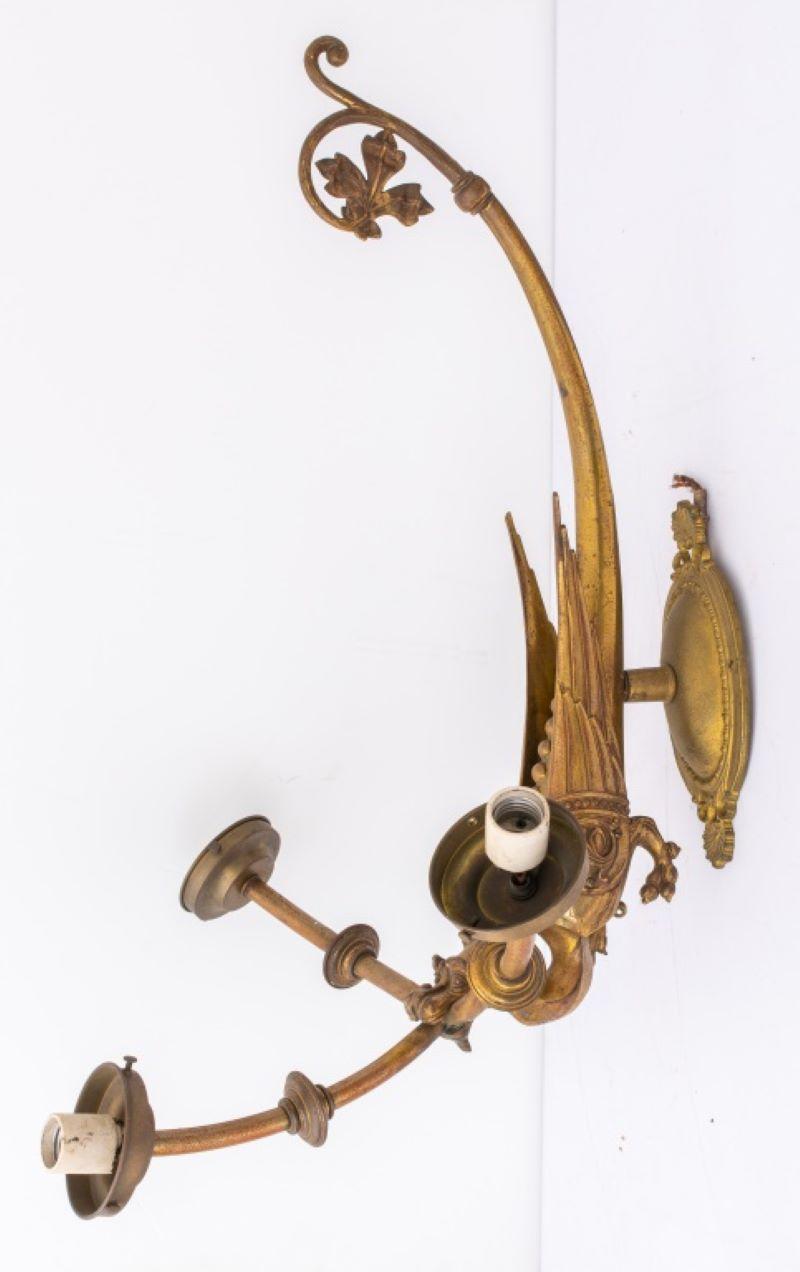 European gilded bronze three light wall applique in the Renaissance Revival or Historicist style, a large winged dragon supports three extruding lamp arms (formerly gas) as it crouches on a scrolling wall plate. Measures: 31