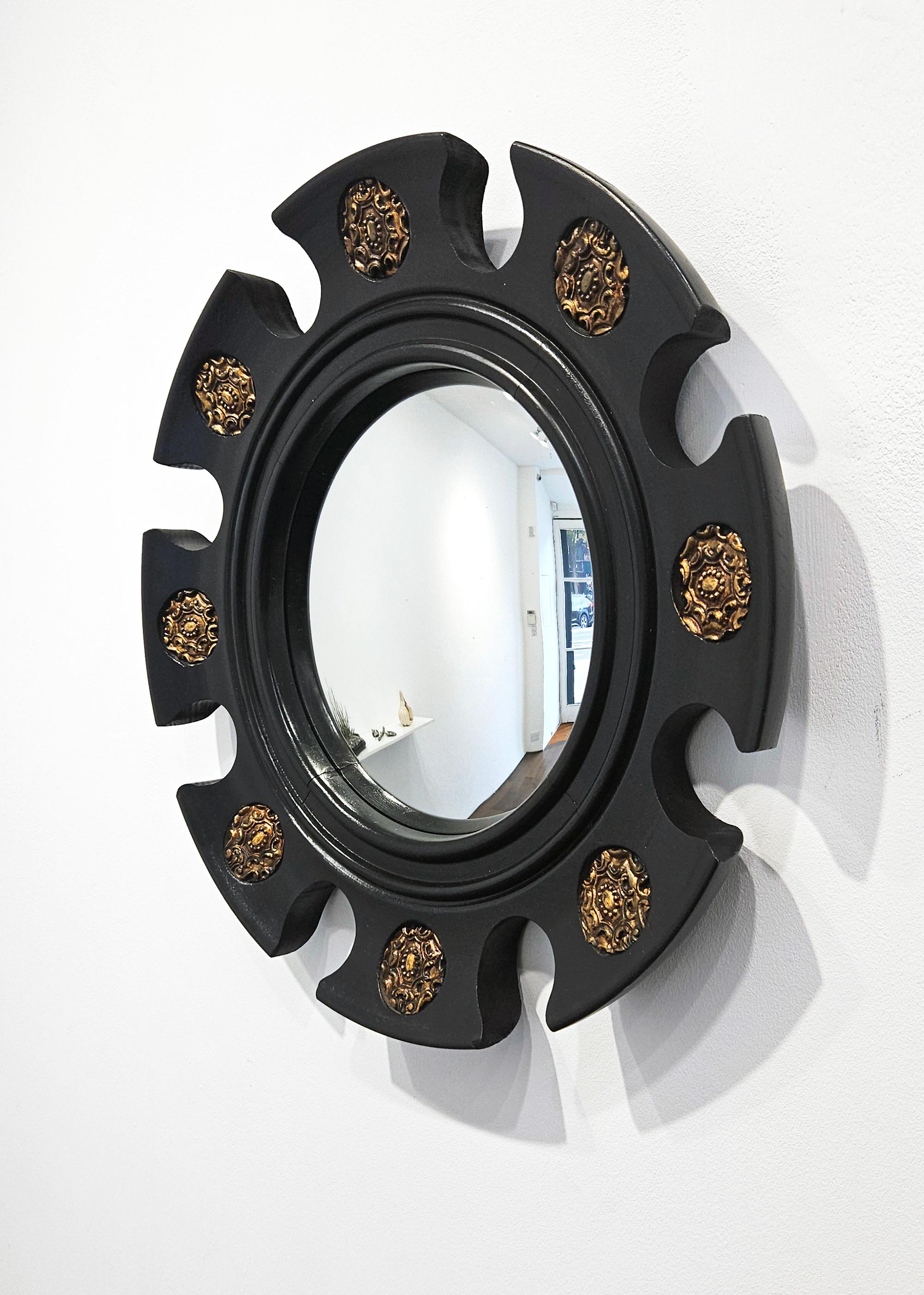 A magnificent and very elegant black and gold mid century ‘Arnolfini’ style sunburst witch’s mirror in the Renaissance Revival style with a hand carved wood frame and circular gilt emblems, made in Spain c. 1950. 

This mirror is very striking and