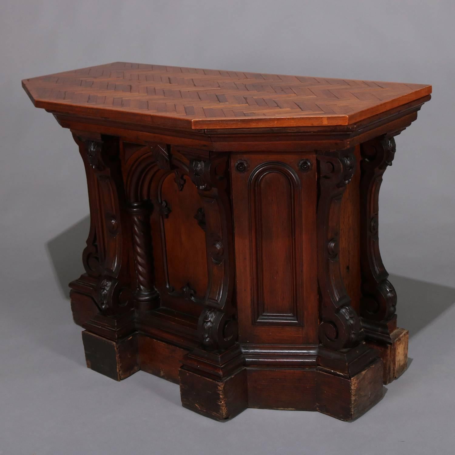 Gothic Renaissance Revival mahogany and walnut presentation podium features parquetry top over base with central Gothic arch flanked by barley twist columns and carved support columns with burl insets, back is open with shelving, circa