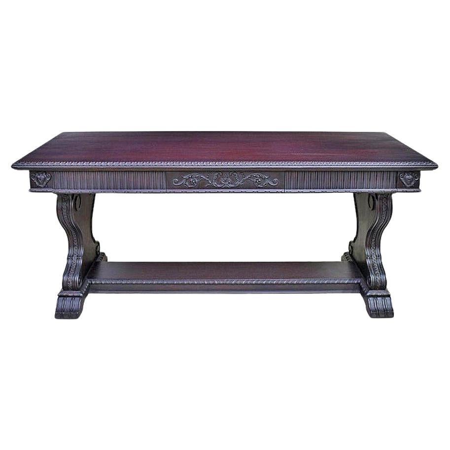 A Renaissance-revival desk or sofa table in walnut with dark, ebonized umber finish & featuring beautiful carvings that include decorative moldings, linen fold panels & acanthus foliage along the apron & drawers, as well as applied papier-mâché