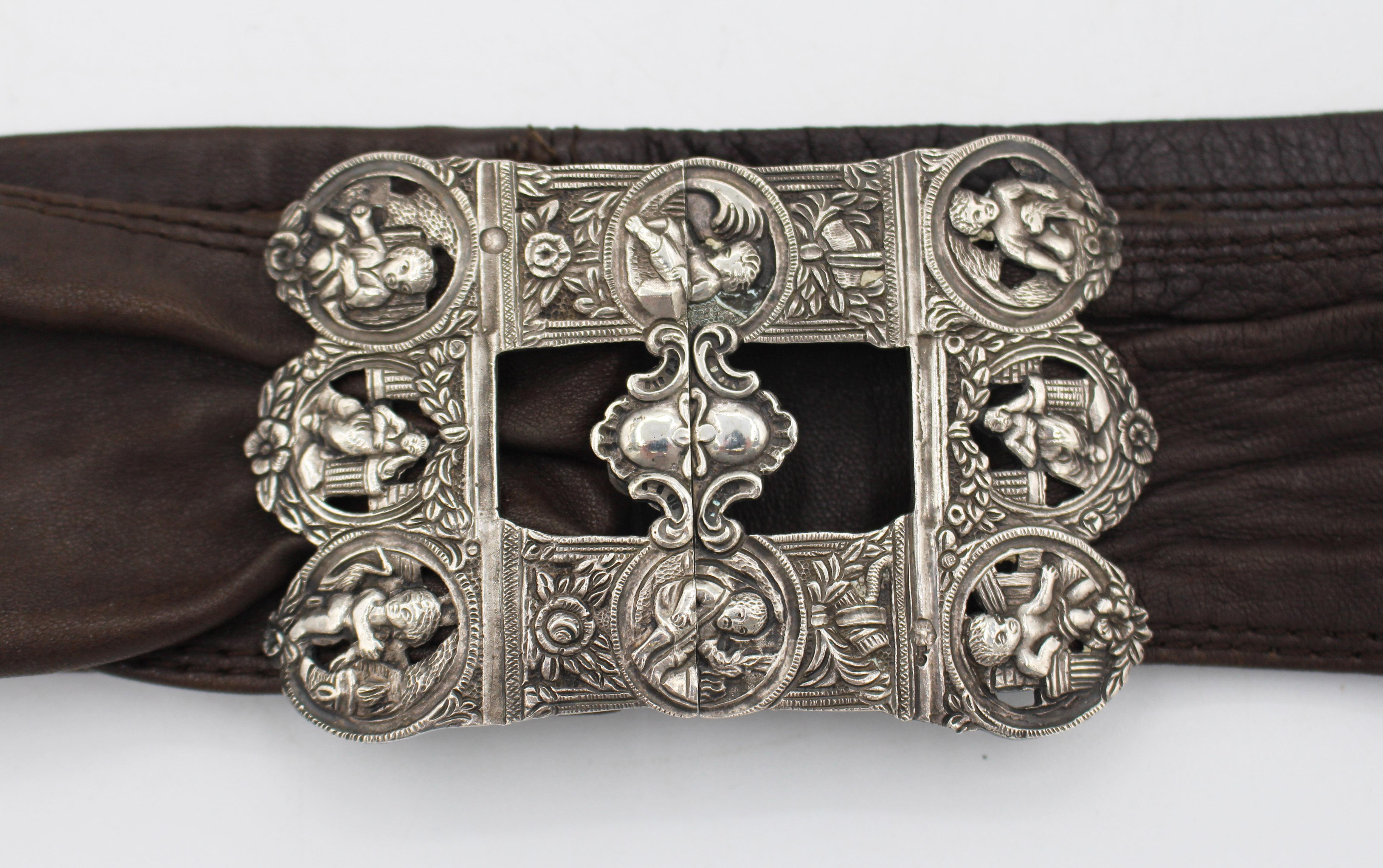 Fibbia da cintura in argento olandese di epoca rinascimentale, ora su una cintura a fascia in pelle. Marchi post 1814 per argento standard .833. Saggiato dopo la seconda guerra mondiale a Schoonhaven (testa con M). Divertenti vignette su ogni metà.