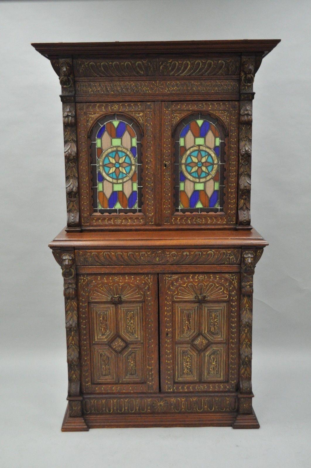 Two-piece antique Renaissance Revival carved oak and leaded stained colored glass cupboard cabinet. Item features finely carved solid oakwood two-part construction, carved lions with iron hoops, single hand dovetailed drawer, two leaded stained