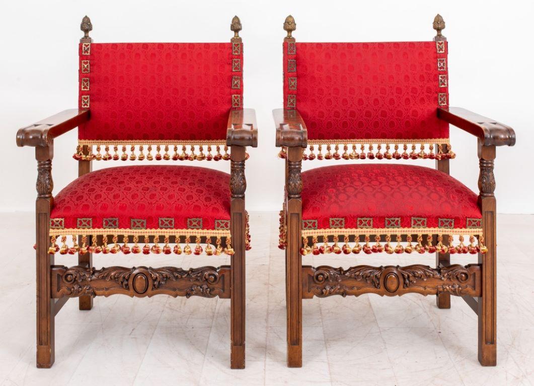 Pair of Renaissance revival mahogany armchairs, a pair, each with finial topped uprights framing an upholstered back issuing scrolling volute arms, above a square upholstered seat supported by four carved legs with carved stretchers. 

Dealer: S138XX