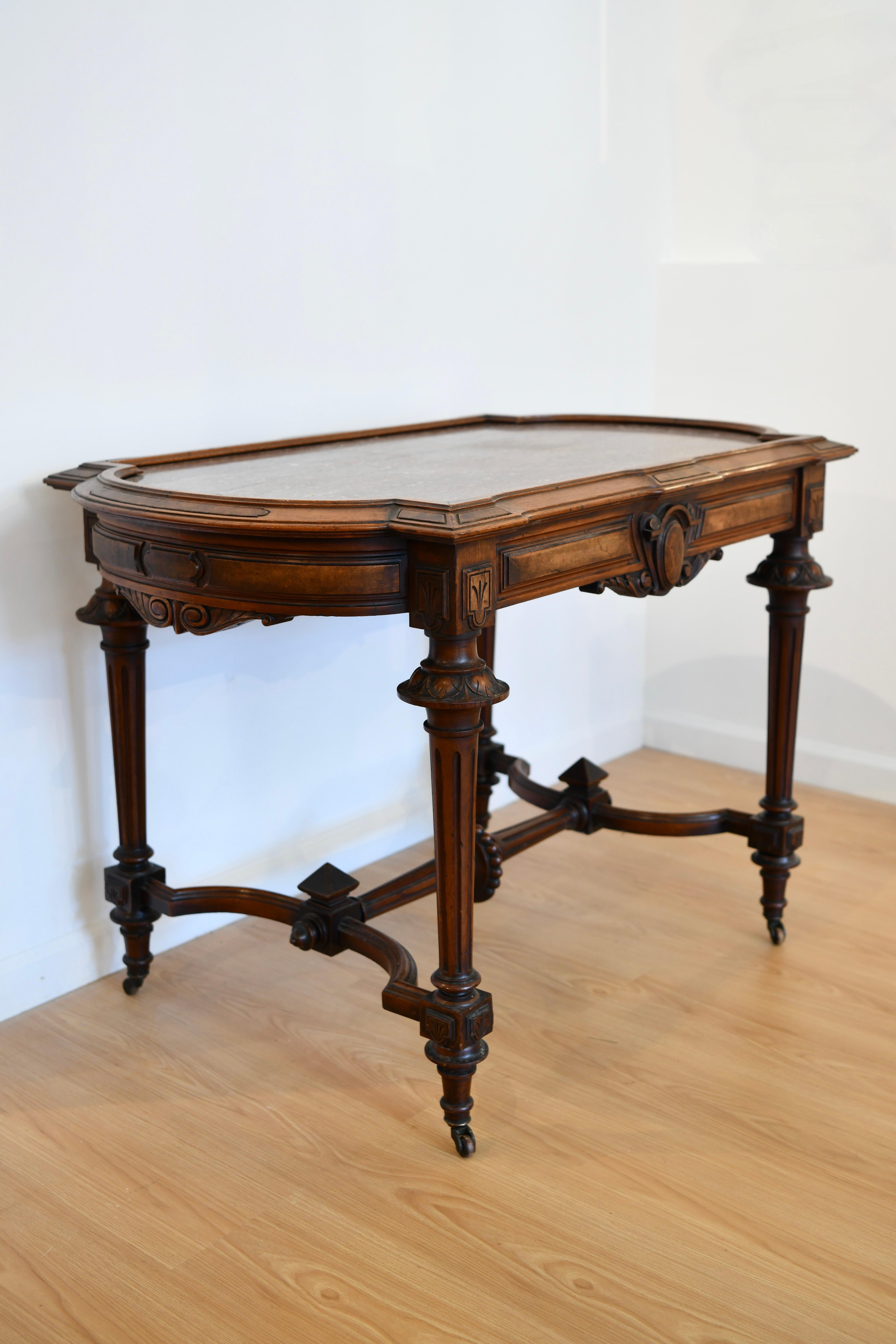 Antique renaissance revival walnut table with carved details, speckled rouge marble top, and on old casters. Dimensions: 21
