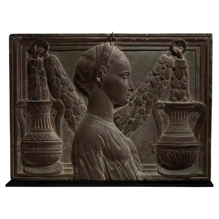 An exceptional high relief Renaissance Revival carved black Pietra Serena panel.

The right facing profile bust of a lady in front of a garland of flowers and leaves suspended above classical vases. Elements overlapping the bolection molded integral