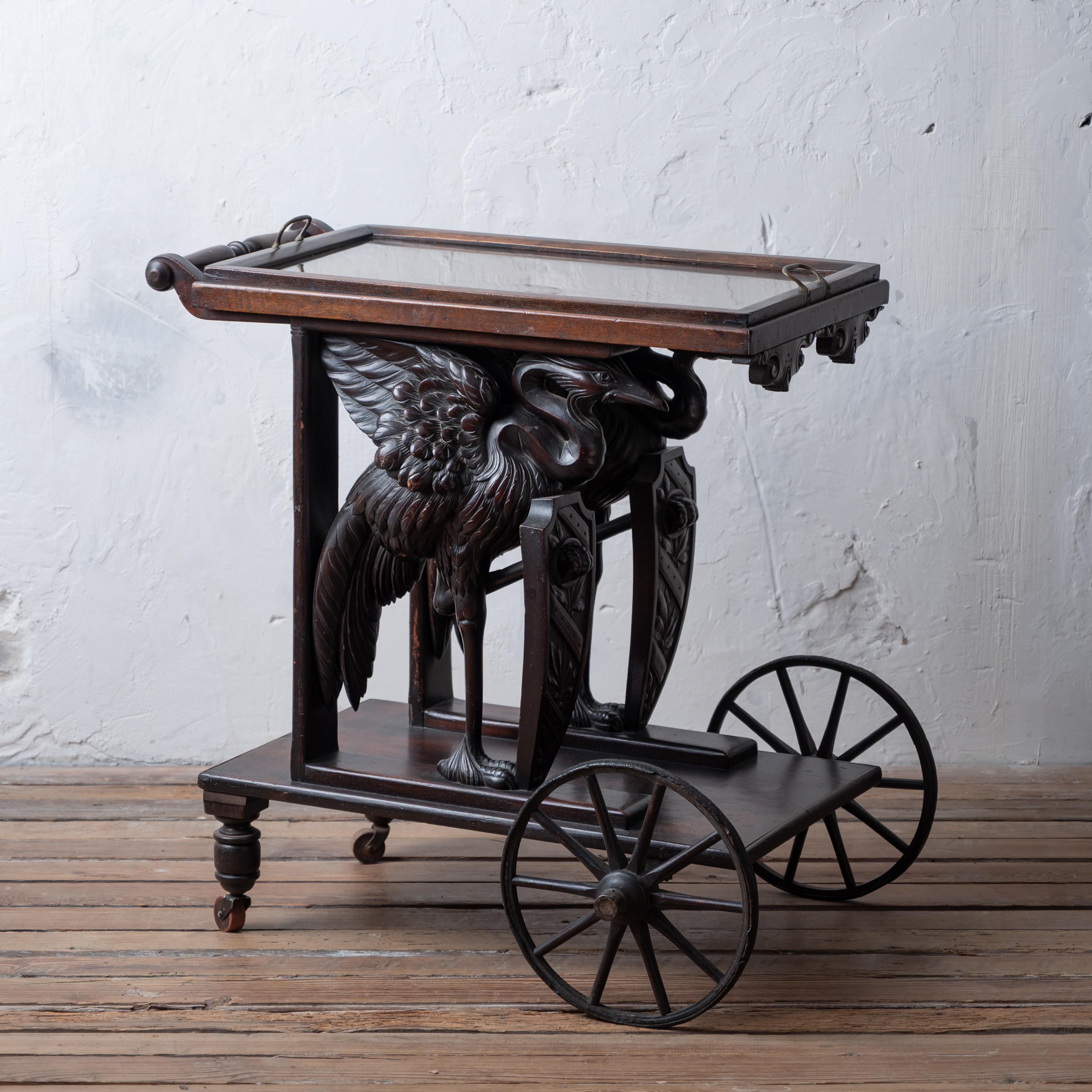 A renaissance revival walnut tea trolley or bar cart with carved herons holding shields, circa 1890.



31 inches wide by 25 inches deep by 31 inches tall; tray dimension 15 by 26 inches



