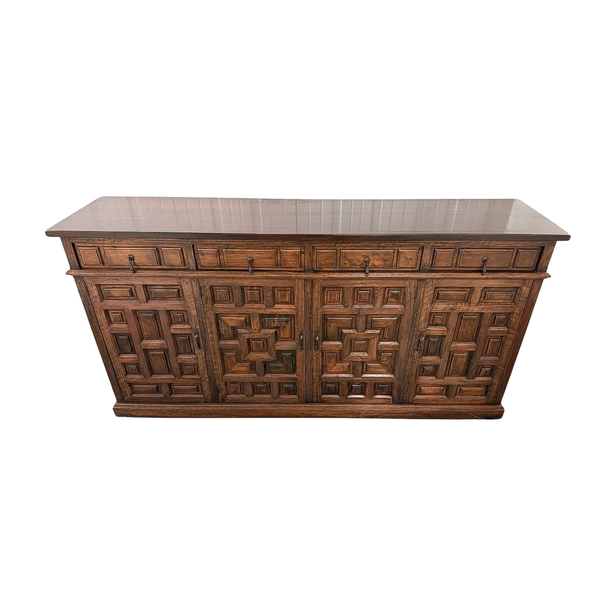 A substantial Renaissance Revival walnut sideboard, late 19th century, with four drawers over four paneled doors. The dimensional geometric carving across the doors and drawers gives the piece a bold, architectural presence. At over six feet wide,