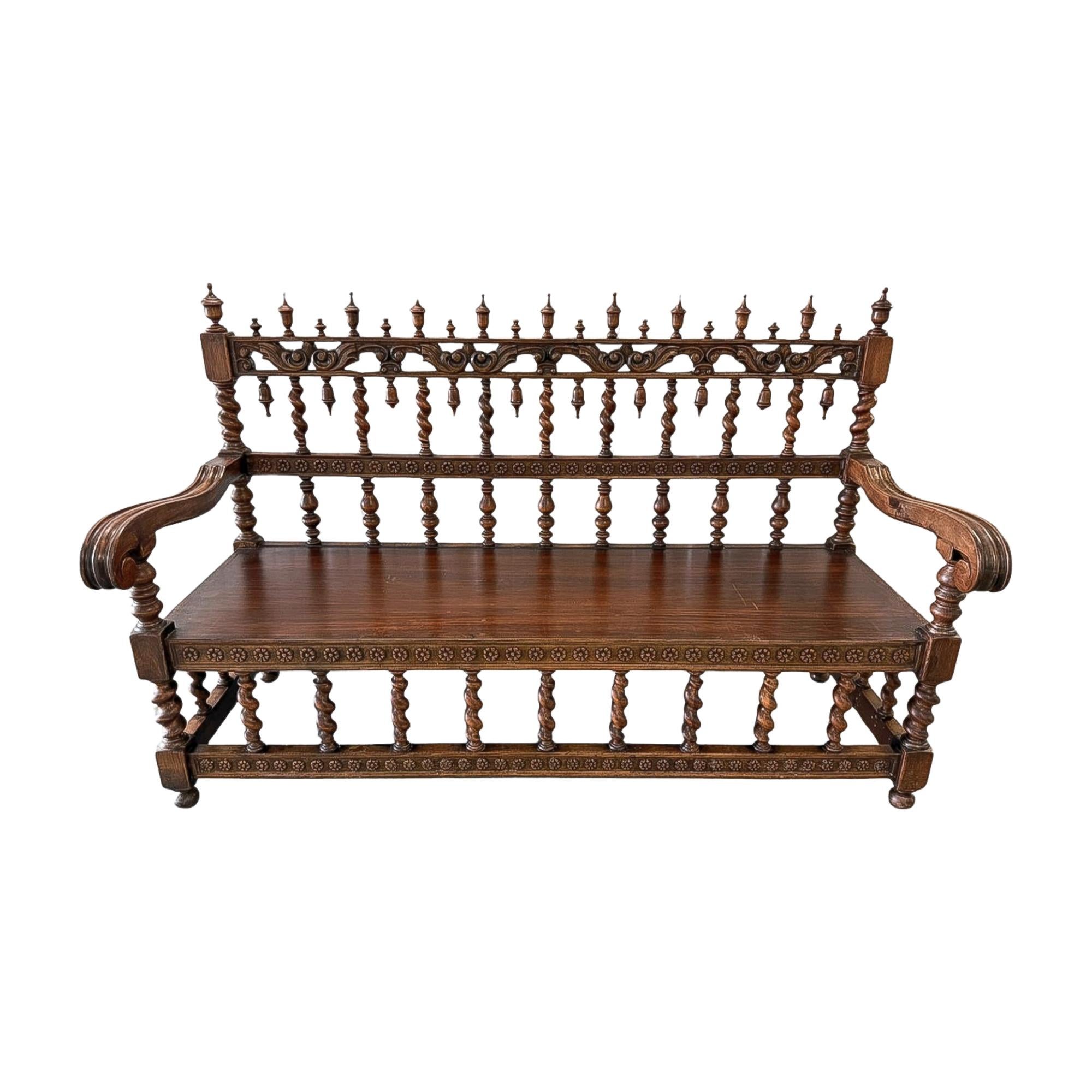 A richly detailed Renaissance Revival settee, late 19th century, crafted in walnut with dramatic turned spindle uprights, scrolled arms, and a carved apron. The architectural back features multiple rows of baluster-turned spindles capped by finials,