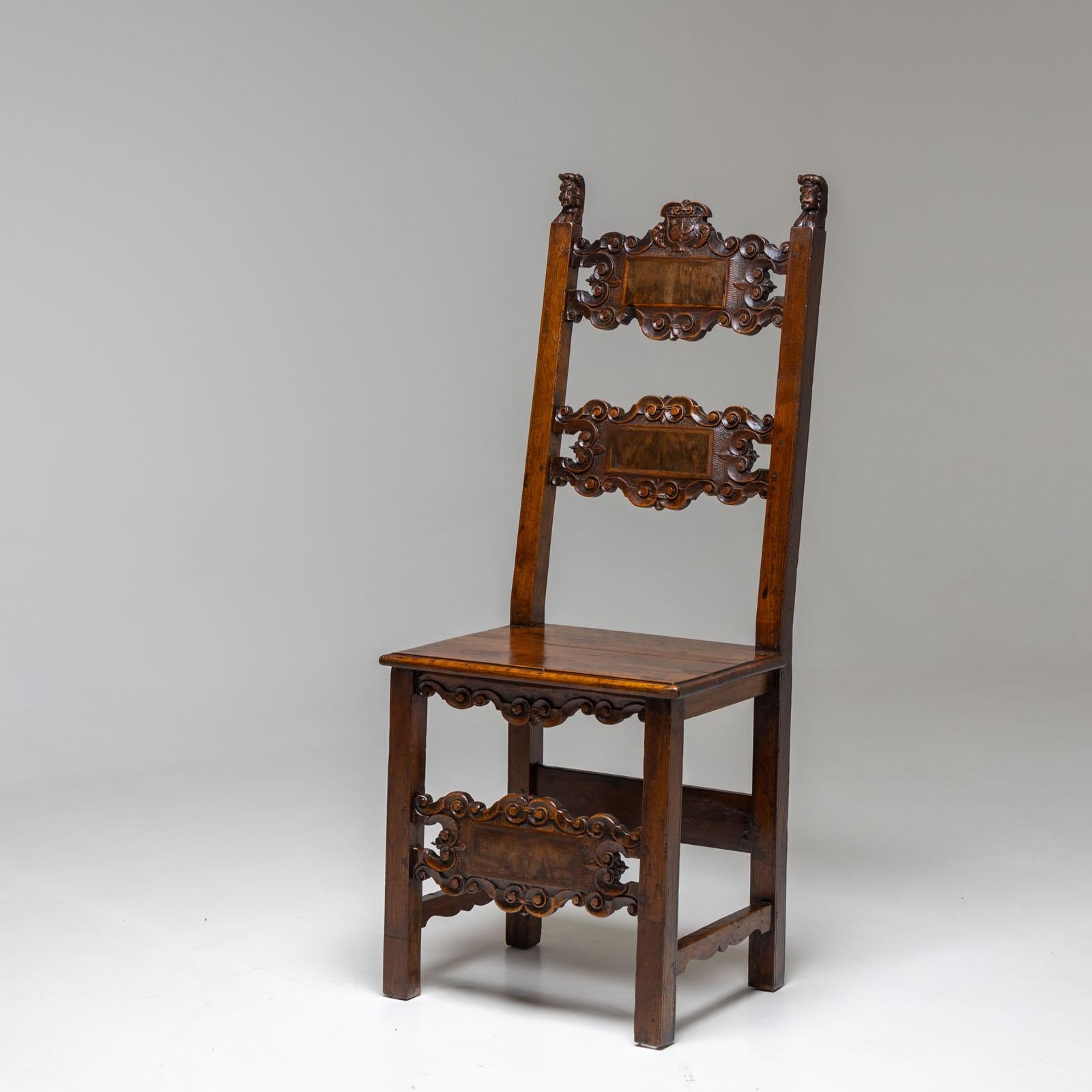 Side Chair made of solid walnut with carved pinnacles in the shape of small busts and volute-decorated intermediate struts on the backrest and front legs. A carved coat of arms cartouche (three stars above a sword arm) crowns the back of the chair.