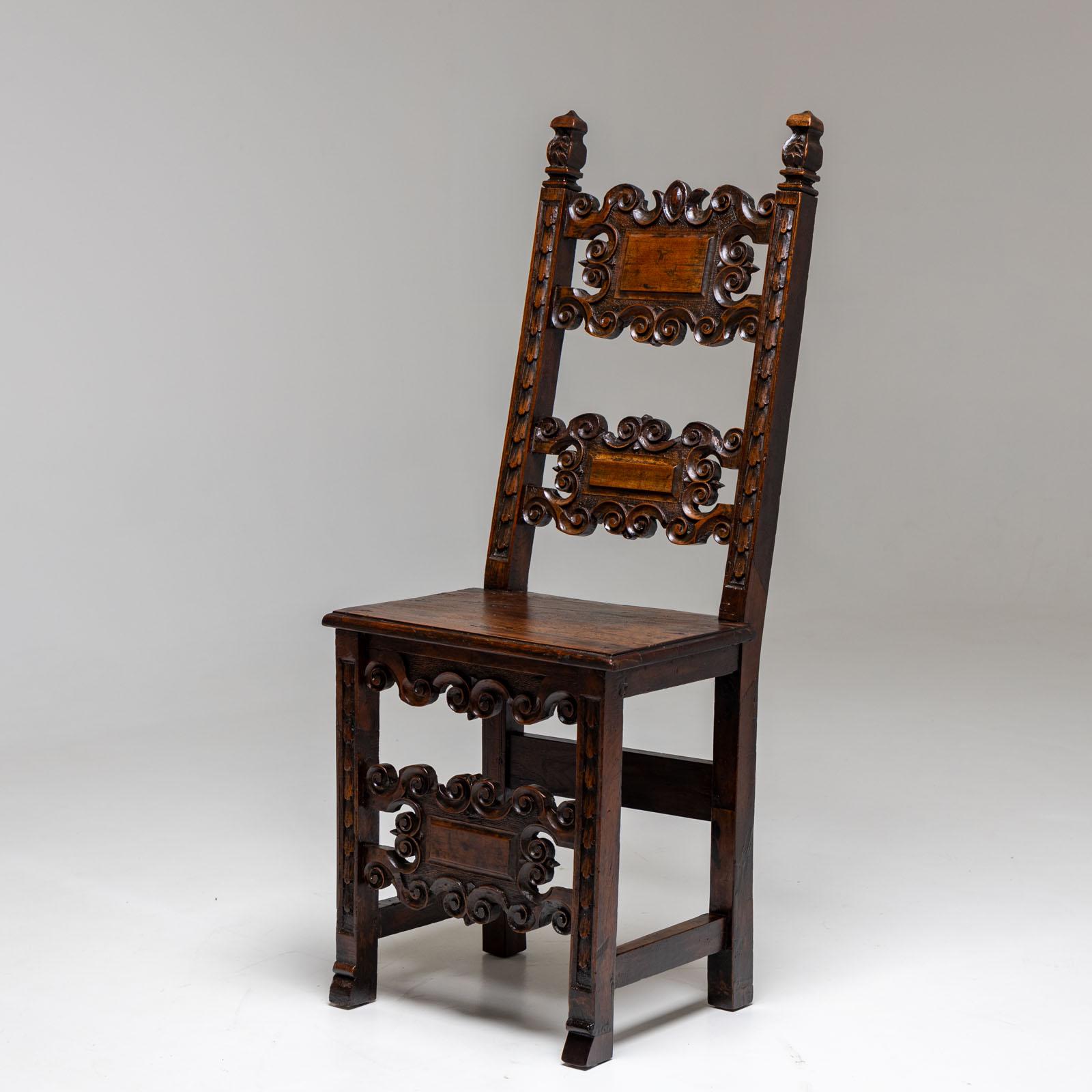 Side chair made of solid walnut with carved pinnacles and volute-decorated intermediate struts on the backrest and front legs. Beautiful authentic patina.
