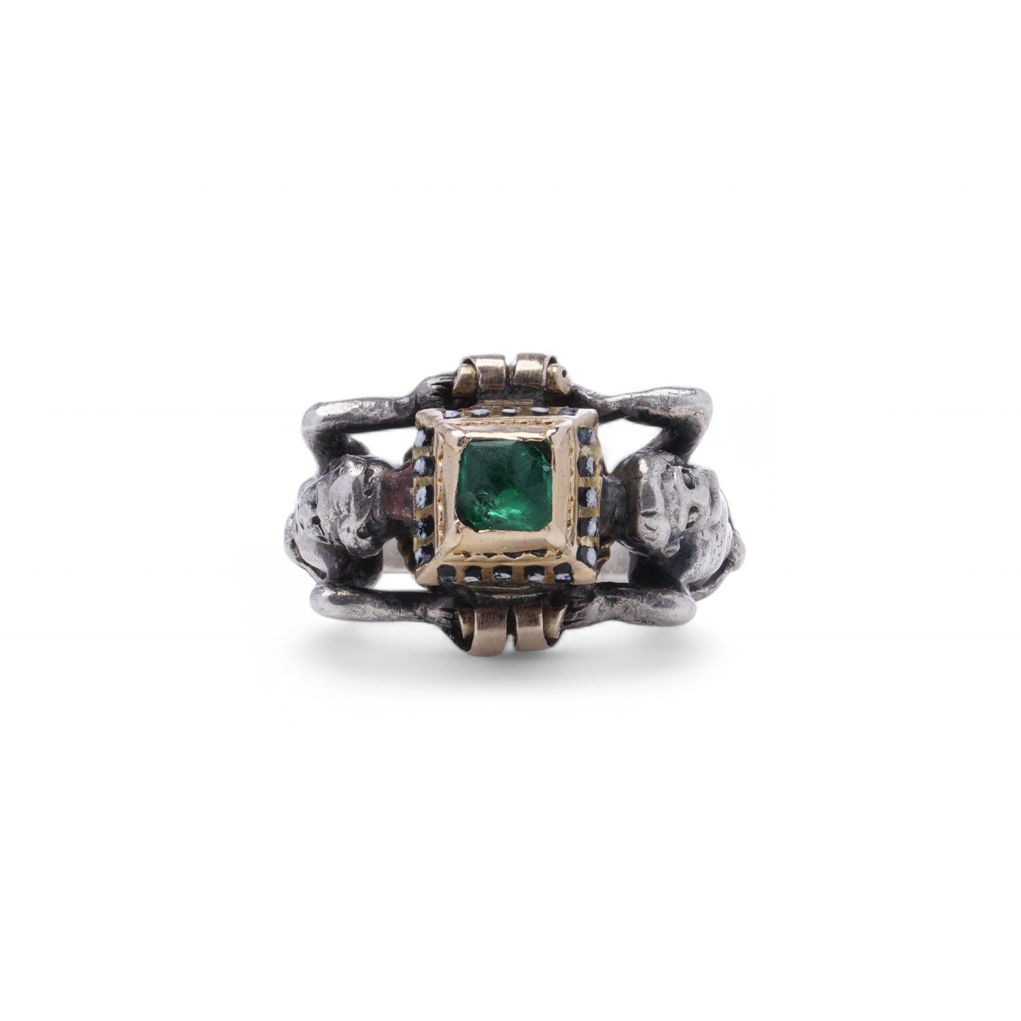 Un affascinante anello rinascimentale realizzato in argento e oro 12 carati, con uno smeraldo centrale a taglio quadrato di circa 0,50 carati. La gemma è inserita in un alto castone d'oro traforato con aperture decorative smaltate, che evidenziano