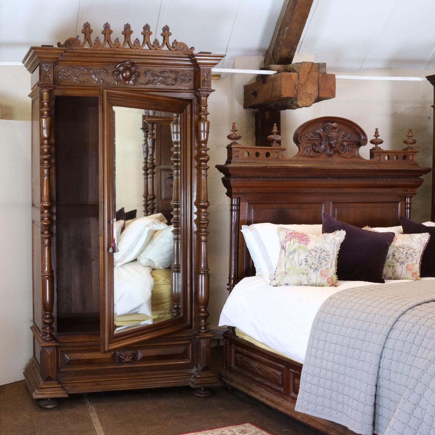 A magnificently carved Renaissance style bedstead in dark walnut, with Greek Goddess on the pediment on the head panel and the Green Man in the centre of the foot end and fluted posts and is on original side runners. 

It is accompanied by two
