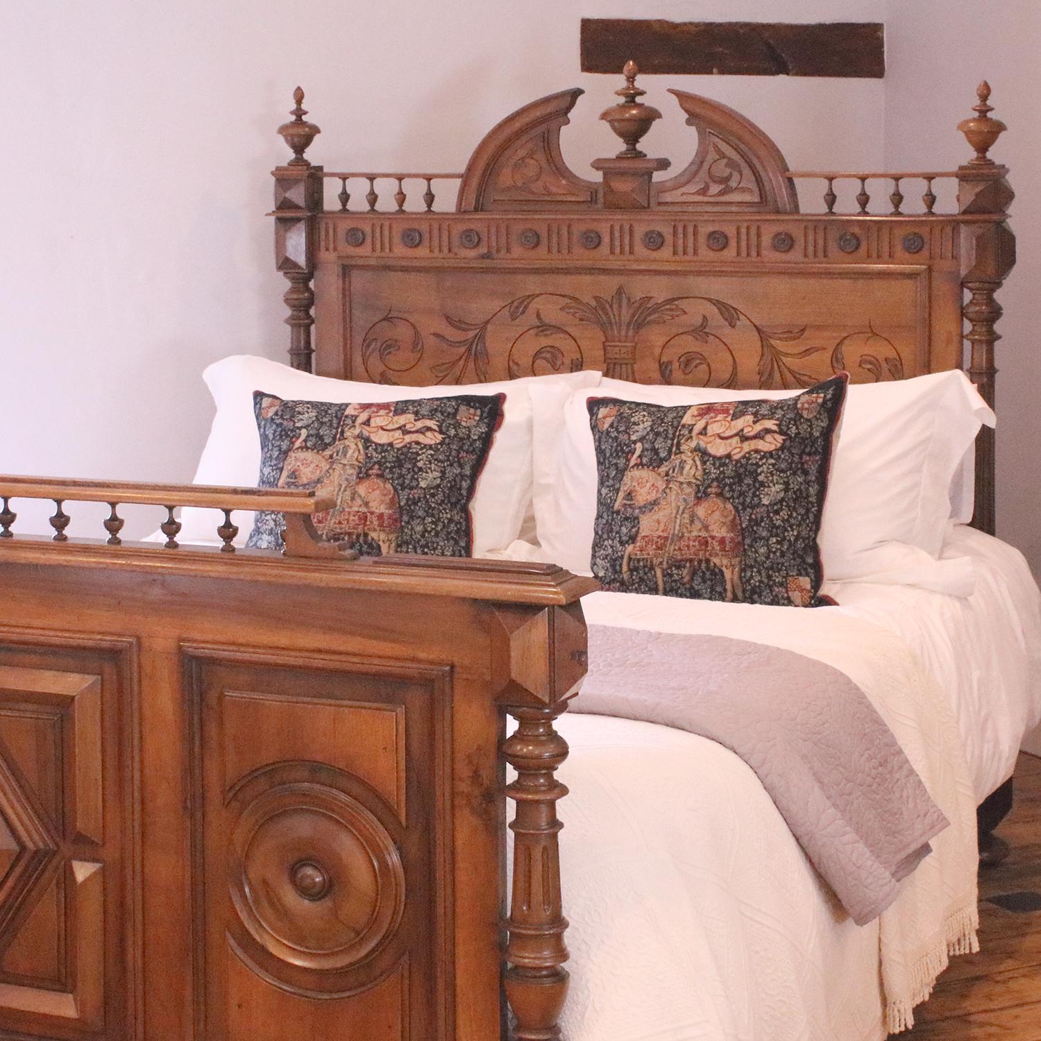 A Renaissance style bedstead in walnut with decoratively carved head panel, ornate pediment and finials, turned posts and fielded panels in the foot board. 

This bed accepts a British king size or American queen size, 5ft wide (60 inches or