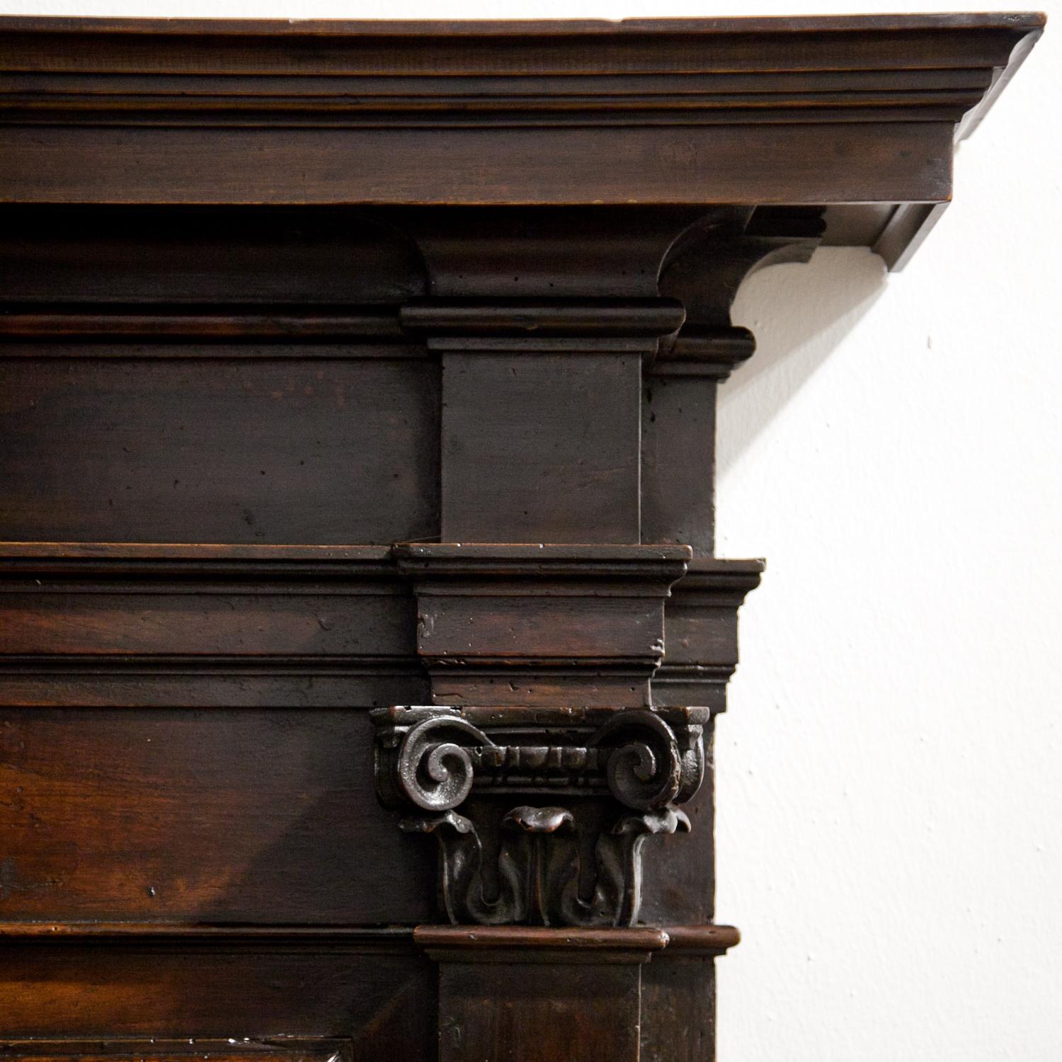 Long Renaissance-style bench, decorated with volutes with mascarons and paw-feet, ionic capitals and a coffered backrest, made out of walnut. The bench was remodeled under use of old parts of a choir stall. The top and base rail are new.