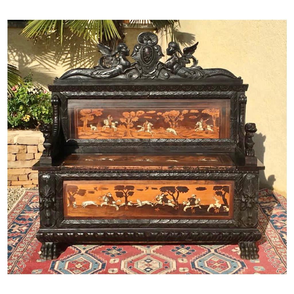 Richly carved Renaissance-style chest-bench in blackened wood and marquetry panels decorated with hunting scenes. The seat lifts to serve as a chest. 
French work from the beginning of the 19th century of good quality.