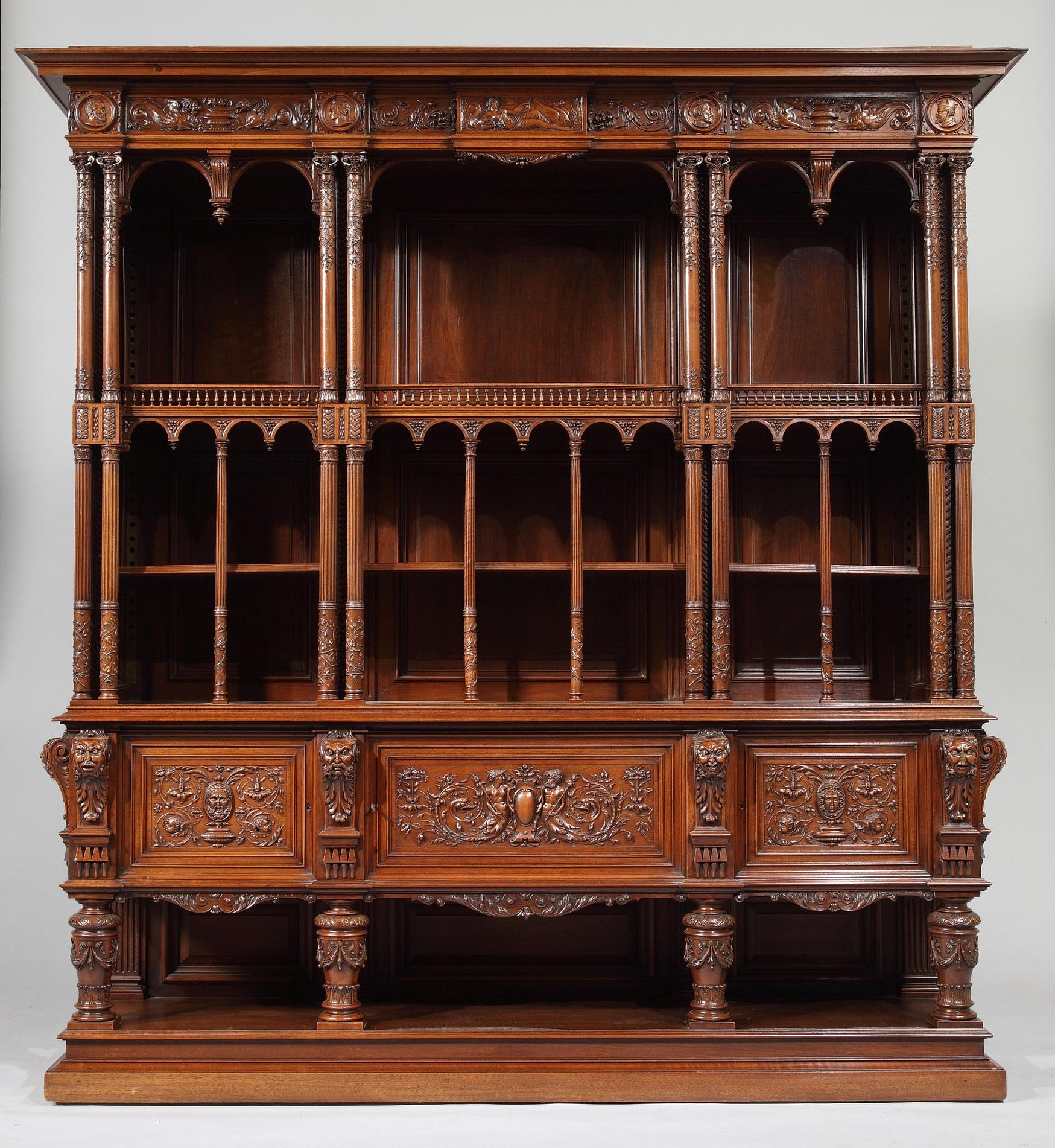An outstanding carved cabinet in the Renaissance style. The upper part consists in two stages with arcades, divided in six compartments by rich columns with Corinthian capitals, and topped by a carved entablature. The lower part opens with three