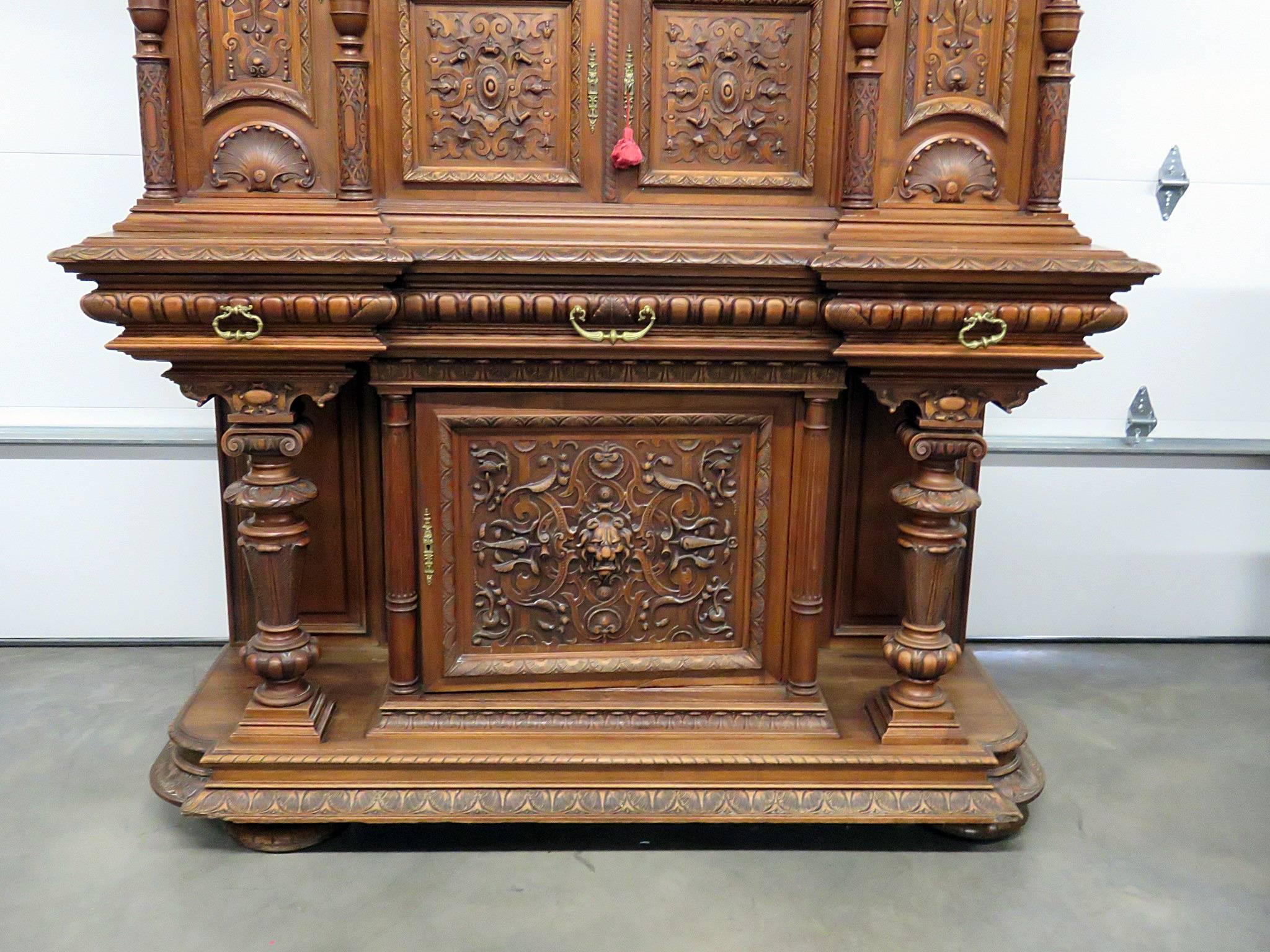 Renaissance style carved cupboard with three drawers, four doors and three shelves.