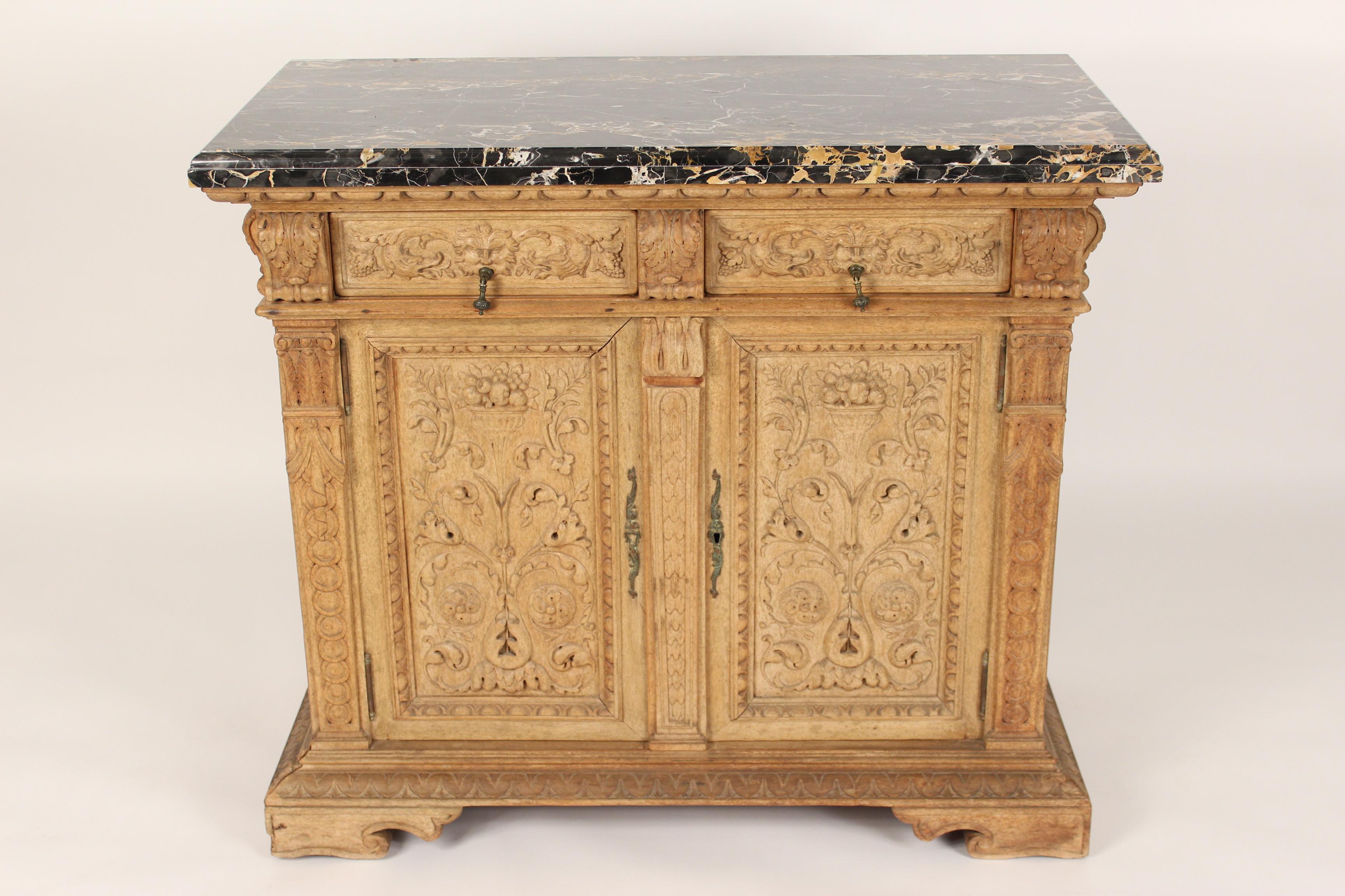 Renaissance style carved bleached walnut credenza with marble top, circa 1920's. The drawers have dolphin and north face carvings, flanked by acanthus carved volutes. The doors have floral and vase carvings. Drawers have dove tail construction.