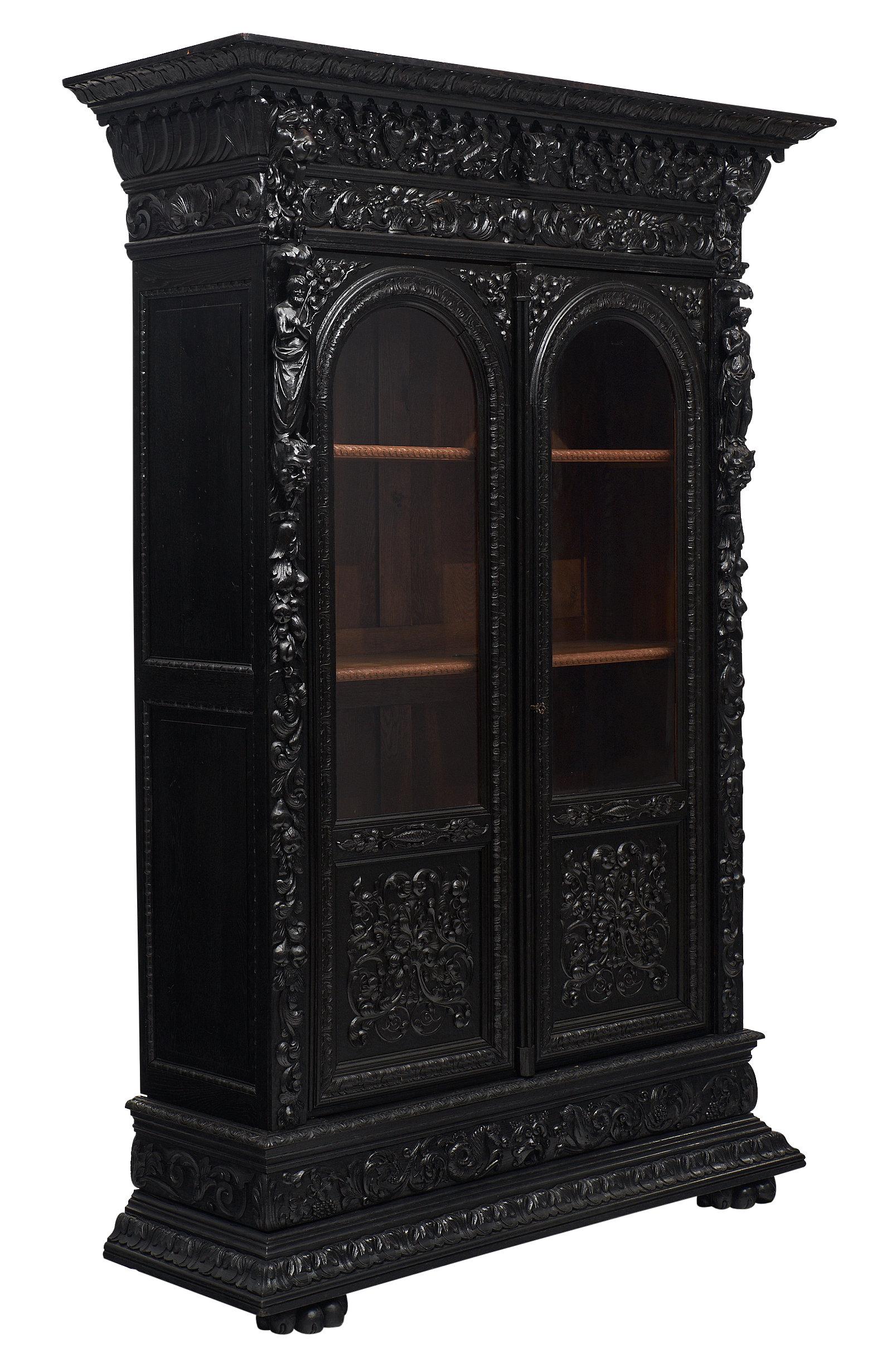 A spectacular French Renaissance style armoire or bookcase in the manner of Hugues Sambin. The renaissance style armoire features rich carving throughout representing foliage, animals, and caryatids. The doors have glass and open up to reveal three