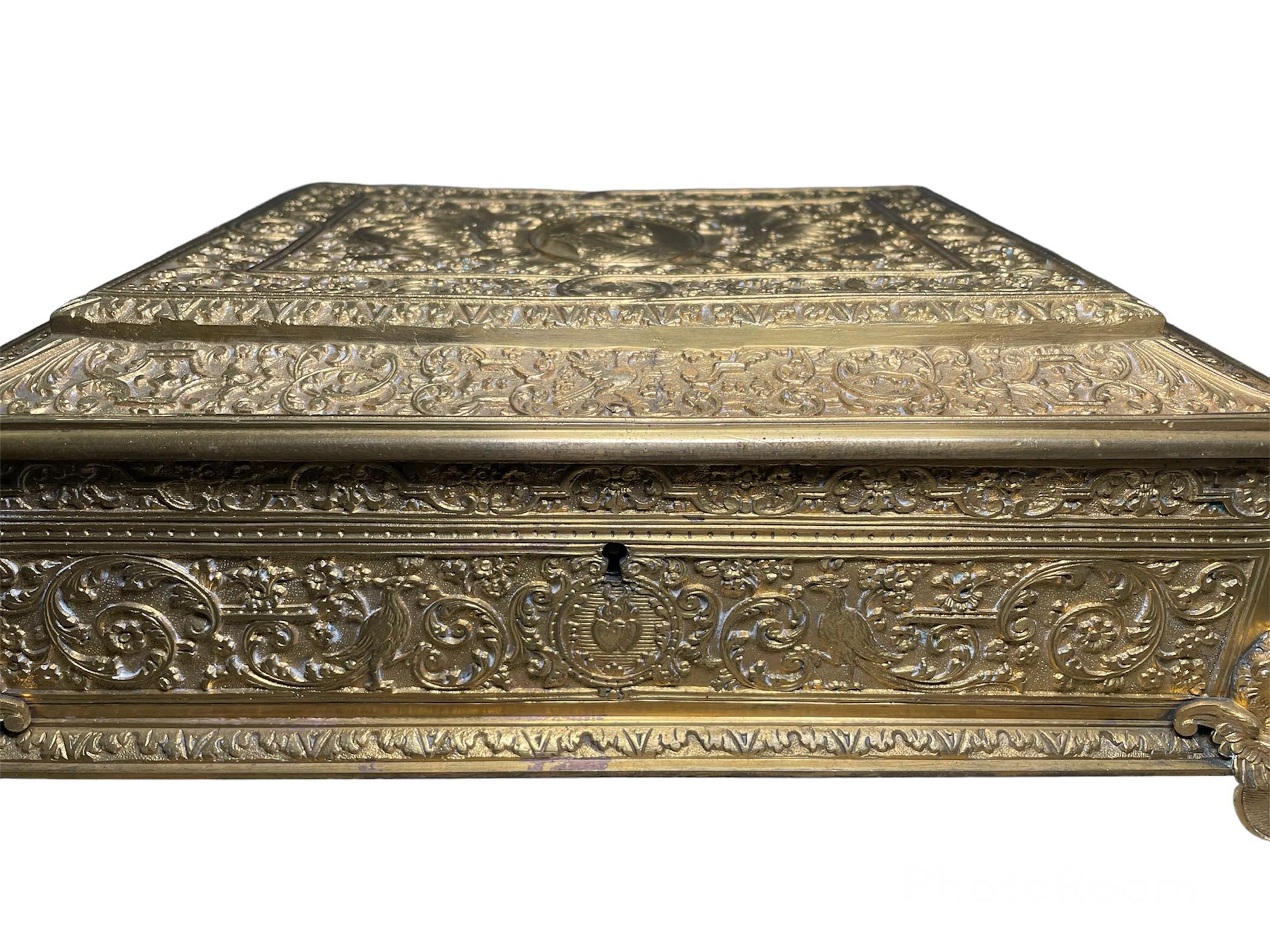 This is a Renaissance style gilt bronze rectangular casket lidded box. It depicts embossed decoration of scrolls of acanthus leaves, birds flowers and hearts around the whole box. In the center of the lid, there is a “cameo” or relief of the profile
