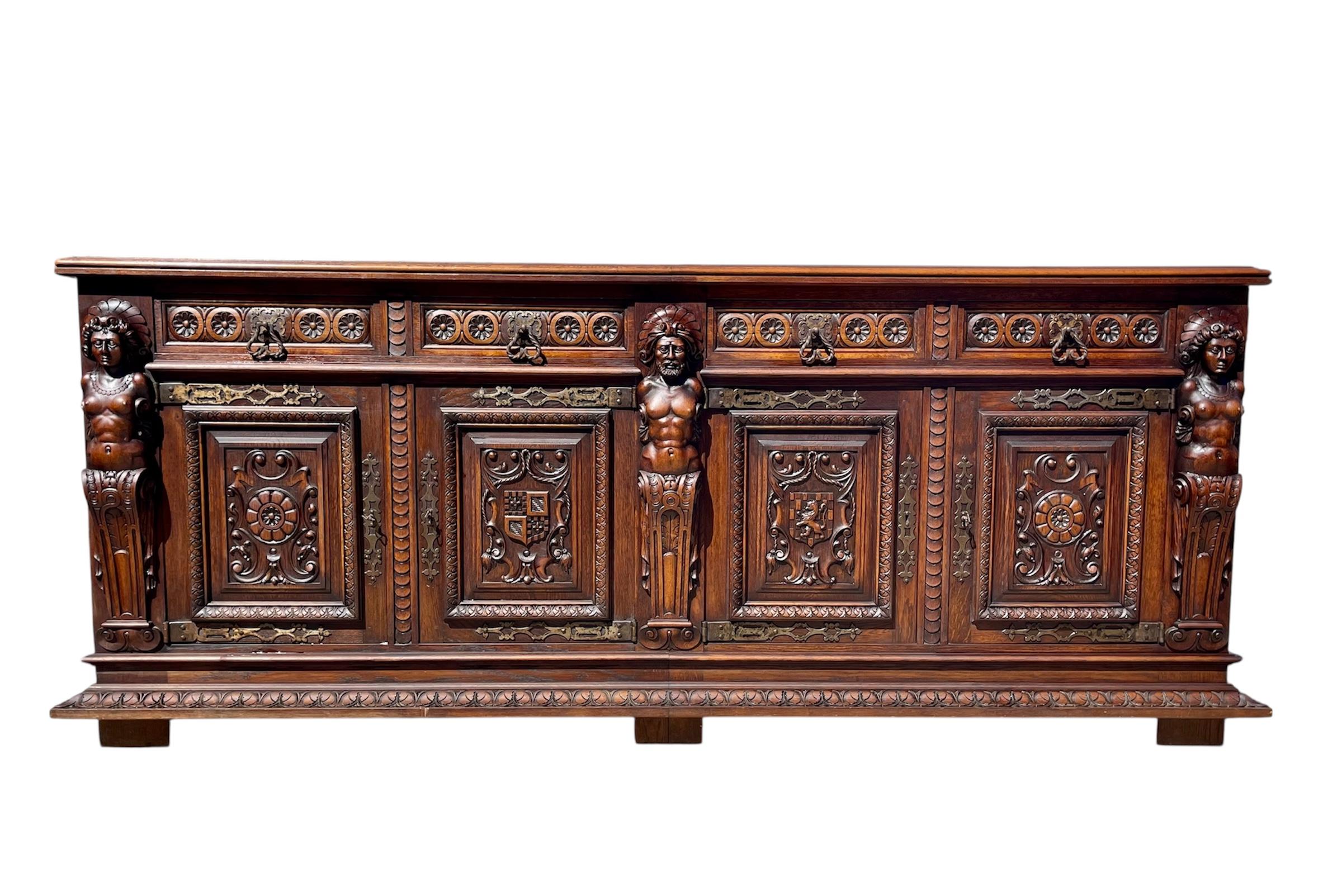 Salle à manger de style Renaissance en chêne richement sculpté composée d'un buffet, d'une armoire/argenterie, d'une table et de 8 chaises. La table comporte deux rallonges glissées sous le plateau. Les chaises sont recouvertes de cuir usagé. 
 Le