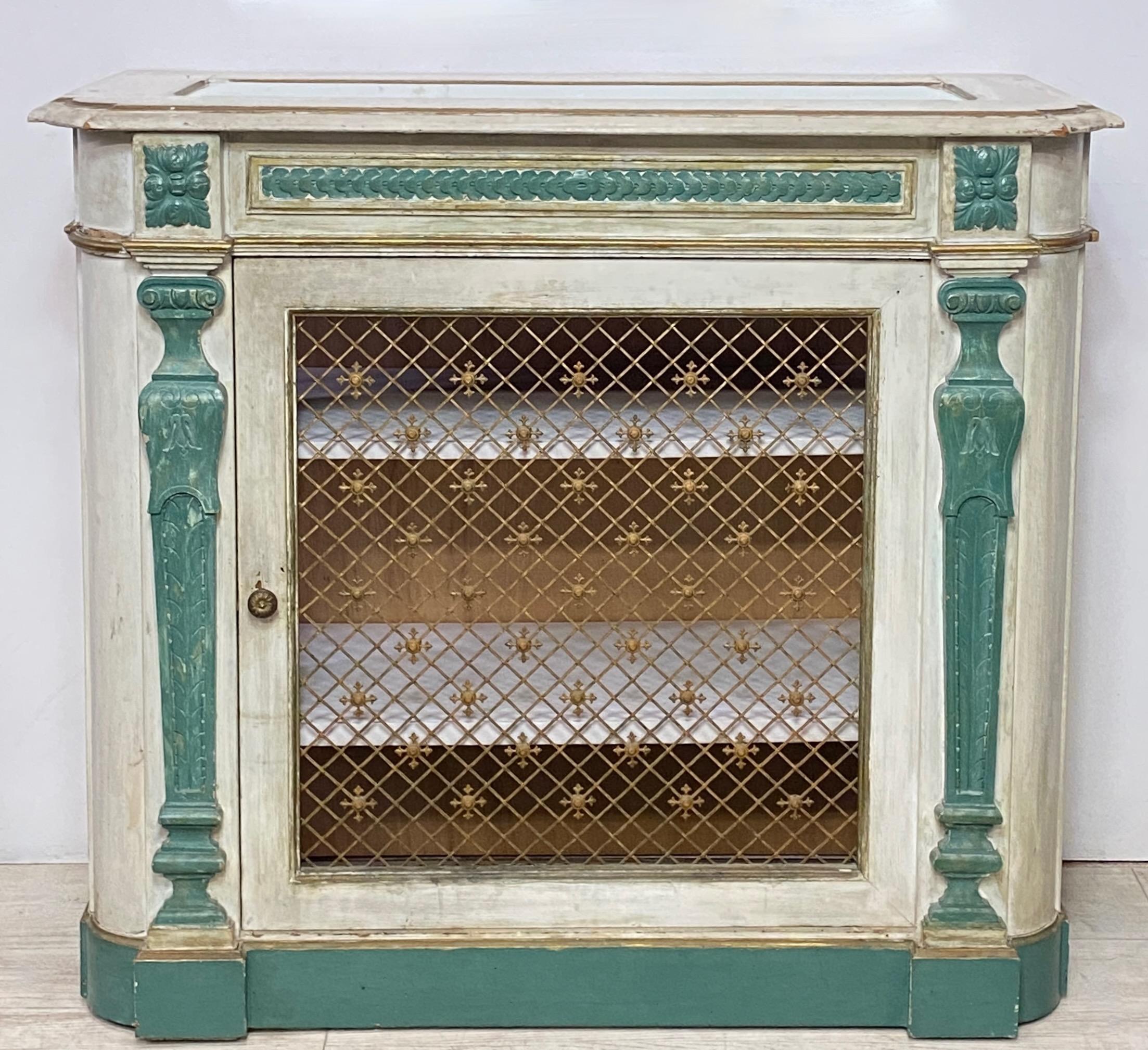Originally custom crafted as a radiator cover (c. 1920) with decorative metal grates in the door and sides
Original paint. 
Inset beveled mirror top. 
It was converted to a stereo cabinet in the 1970s, and had silk fabric behind the 3 metal grates.