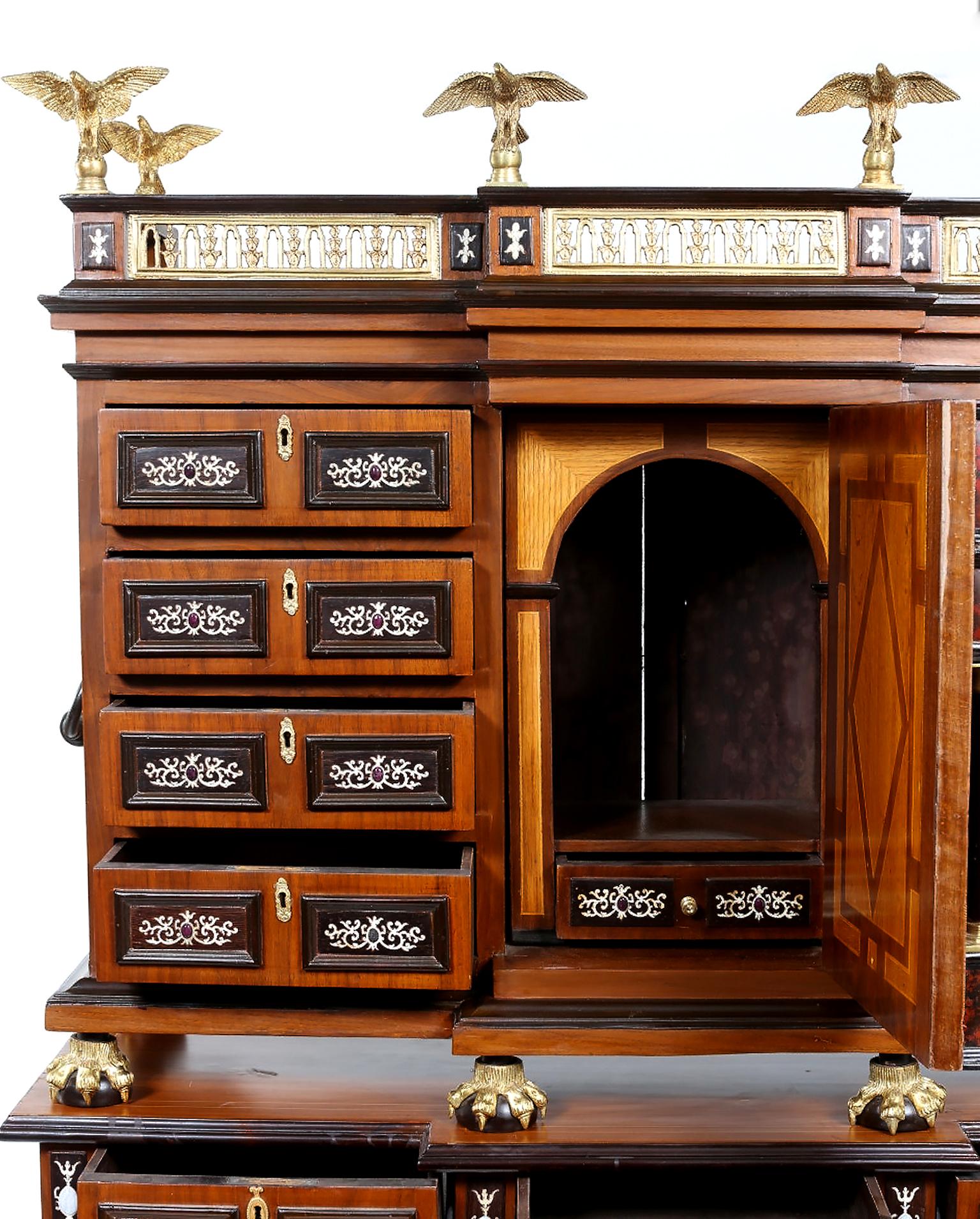 Renaissance style Spanish Vargueno cabinet on stand. Block front with ornately pierced ormolu gallery with eagle finials over a central door with columns flanked by eight drawers. Four on each side on ball and claw feet, resting on three drawer