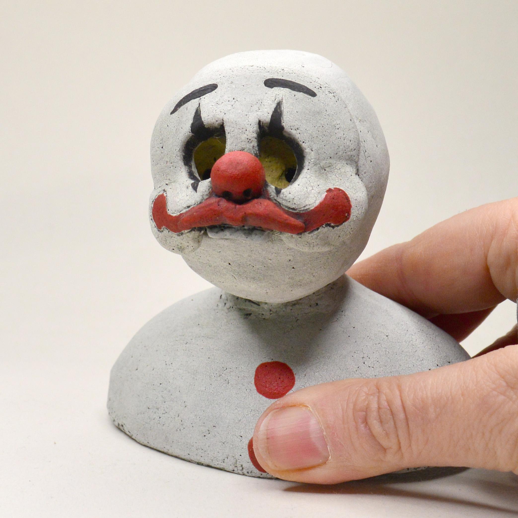 Pineco number 0011 Original Ceramic sculpture with clown mask representing melancholic reality hidden underneath the happy façade.

Meet a variety of characters with distinct masks and postures. These sculptures are fascinating and make you curious,