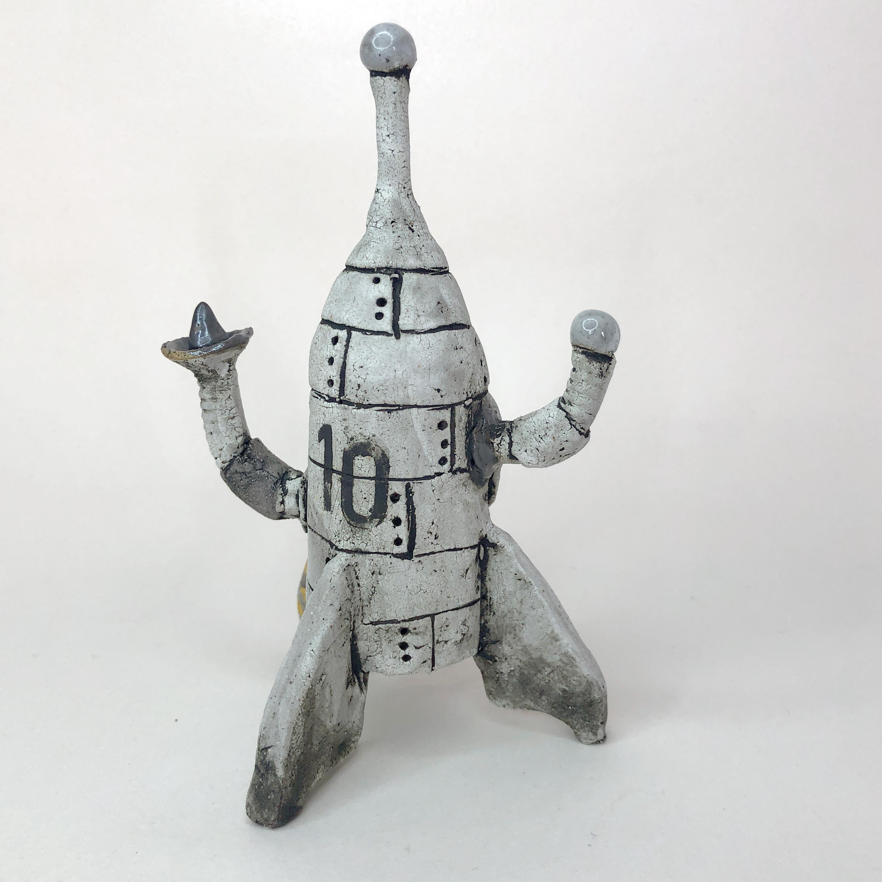 Presenting a stoneware sculpture featuring a petite rocket, adorned with a prominent number 10 and striking white paint with contrasting orange stripes. The sculpture's design exudes simplicity, reminiscent of classic cartoon aesthetics.

The grungy