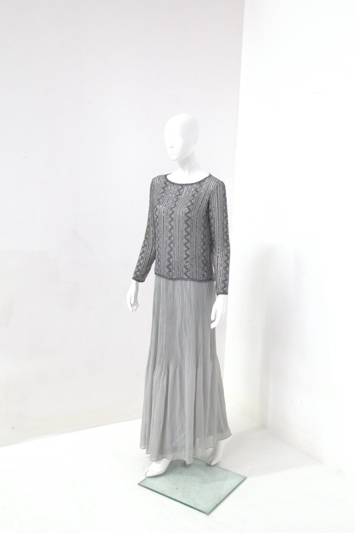 Robe de soirée élégante, phénoménale, raffinée et fine de la célèbre maison de couture italienne Renato Balestra des années 70-80.
La robe est faite en deux parties : jupe et chemise.
La jupe est une élégante mousseline de soie grise très légère et