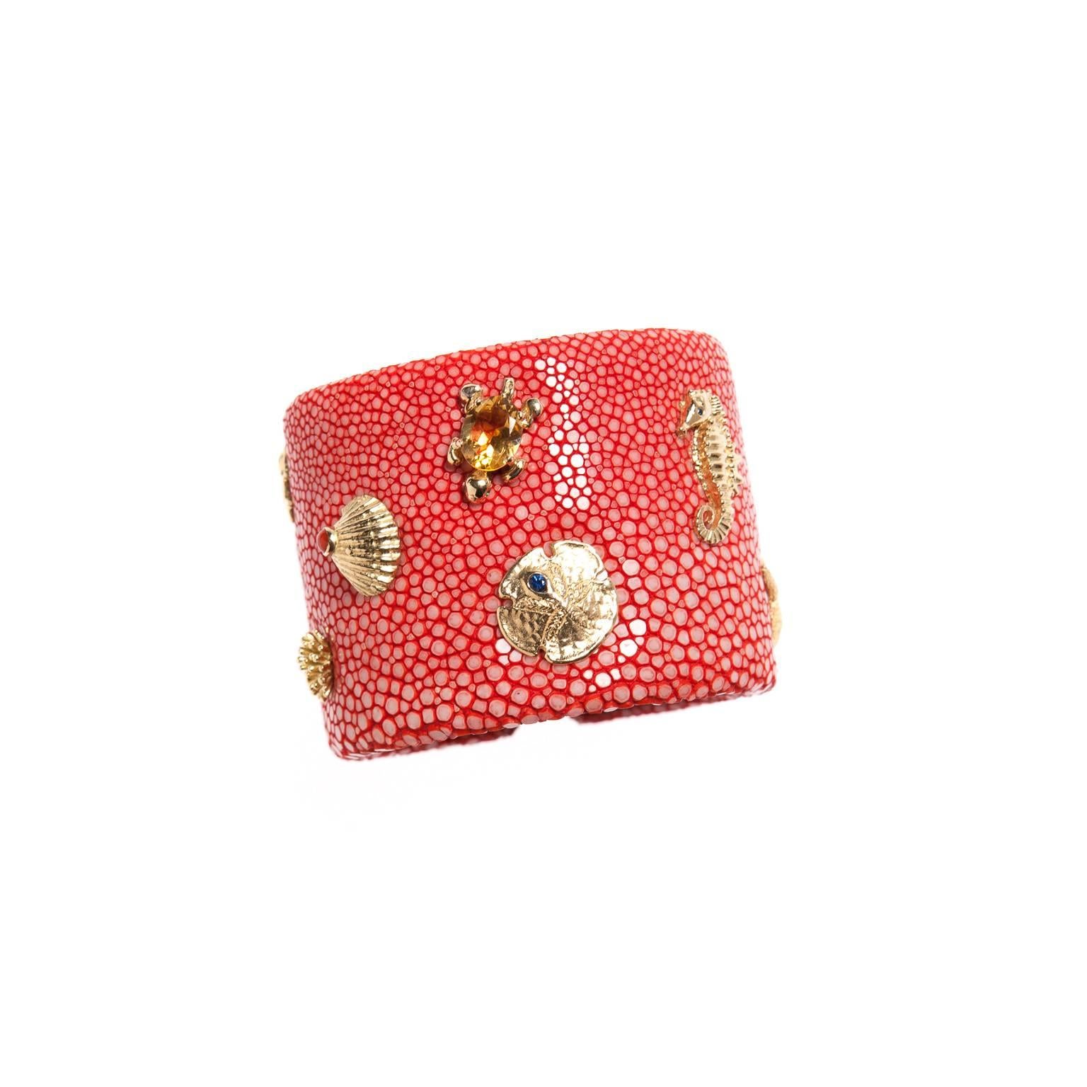 A Renato Cipullo cuff bracelet of genuine coral colored Shagreen with 18k yellow gold seahorse, turtle, starfish, coral and shells each with details of citrine, sapphires, emeralds and coral, 9 in total.