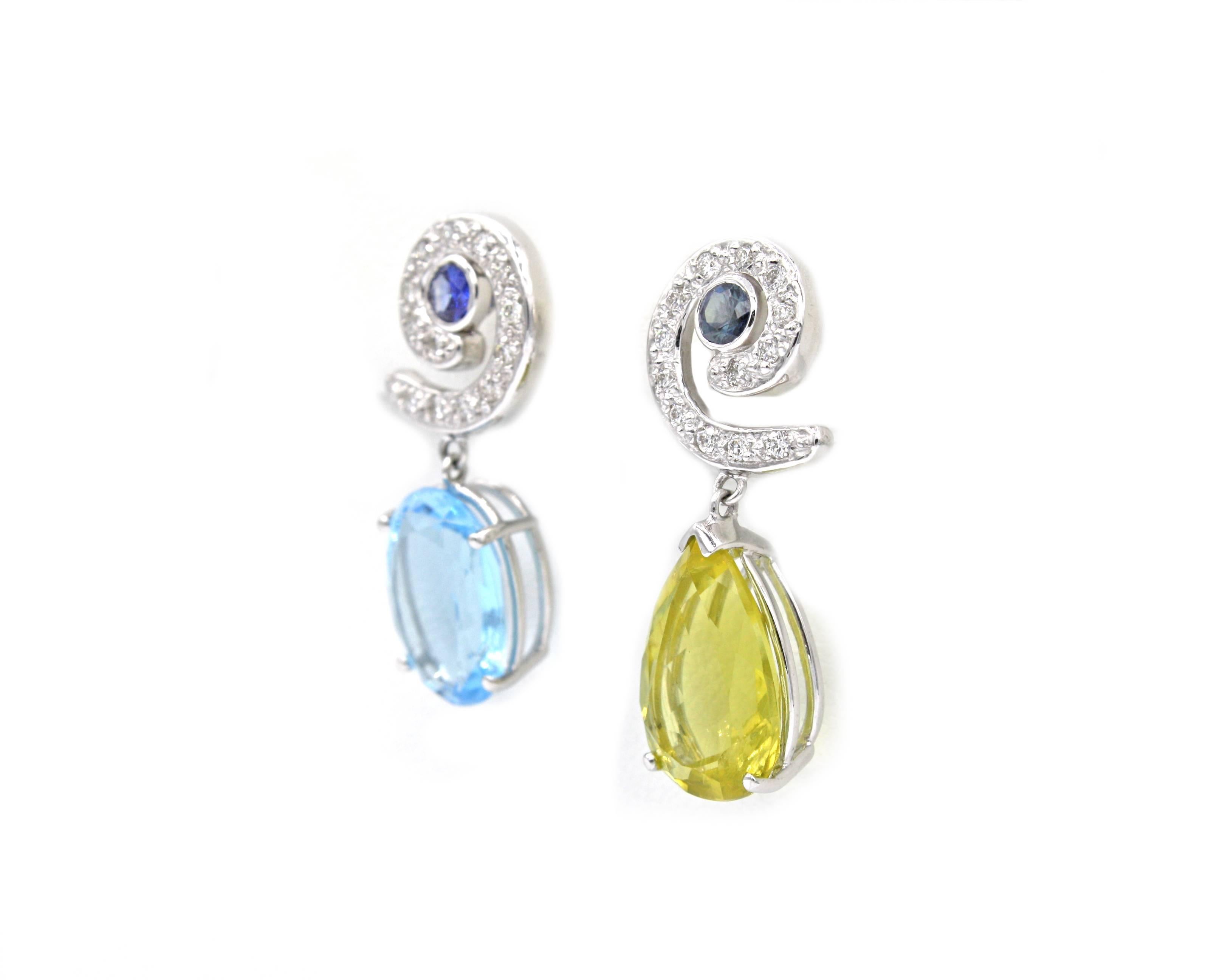 A unique pair of Renato Cipullo earrings, these feature differing yet complimentary stones.  The 5.5ct pear shape yellow beryl and 7ct oval shape blue topaz hang from 18k white gold spirals set with sapphires and 26 diamonds.  