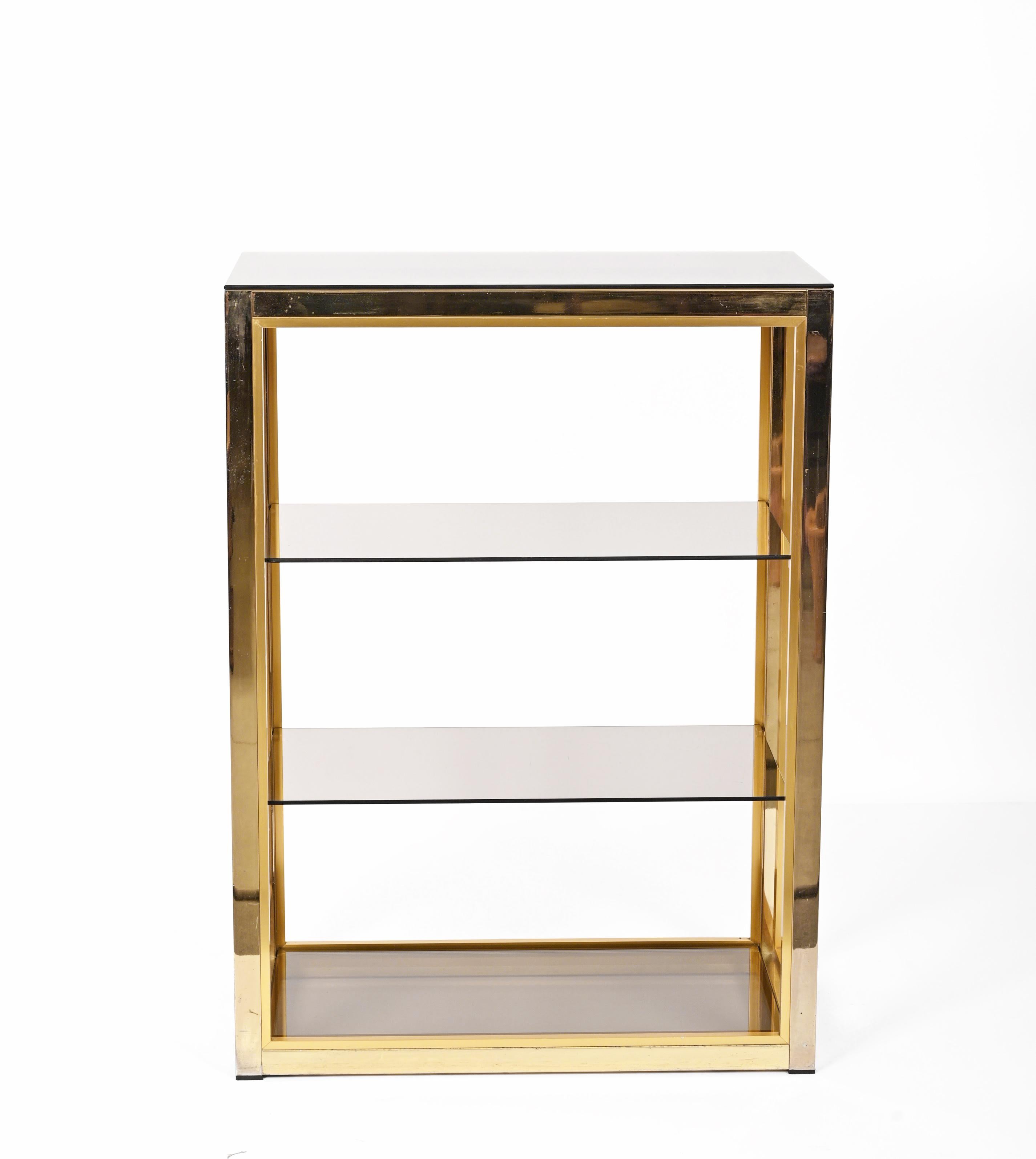 Incredible Hollywood Regency bookcase or etagere in gilt brass with four crystal glass shelves. This fantastic piece was designed and signed by Renato Zevi during ??the 1970s in Italy.

The exceptional materials will surprise you: the pure crystal