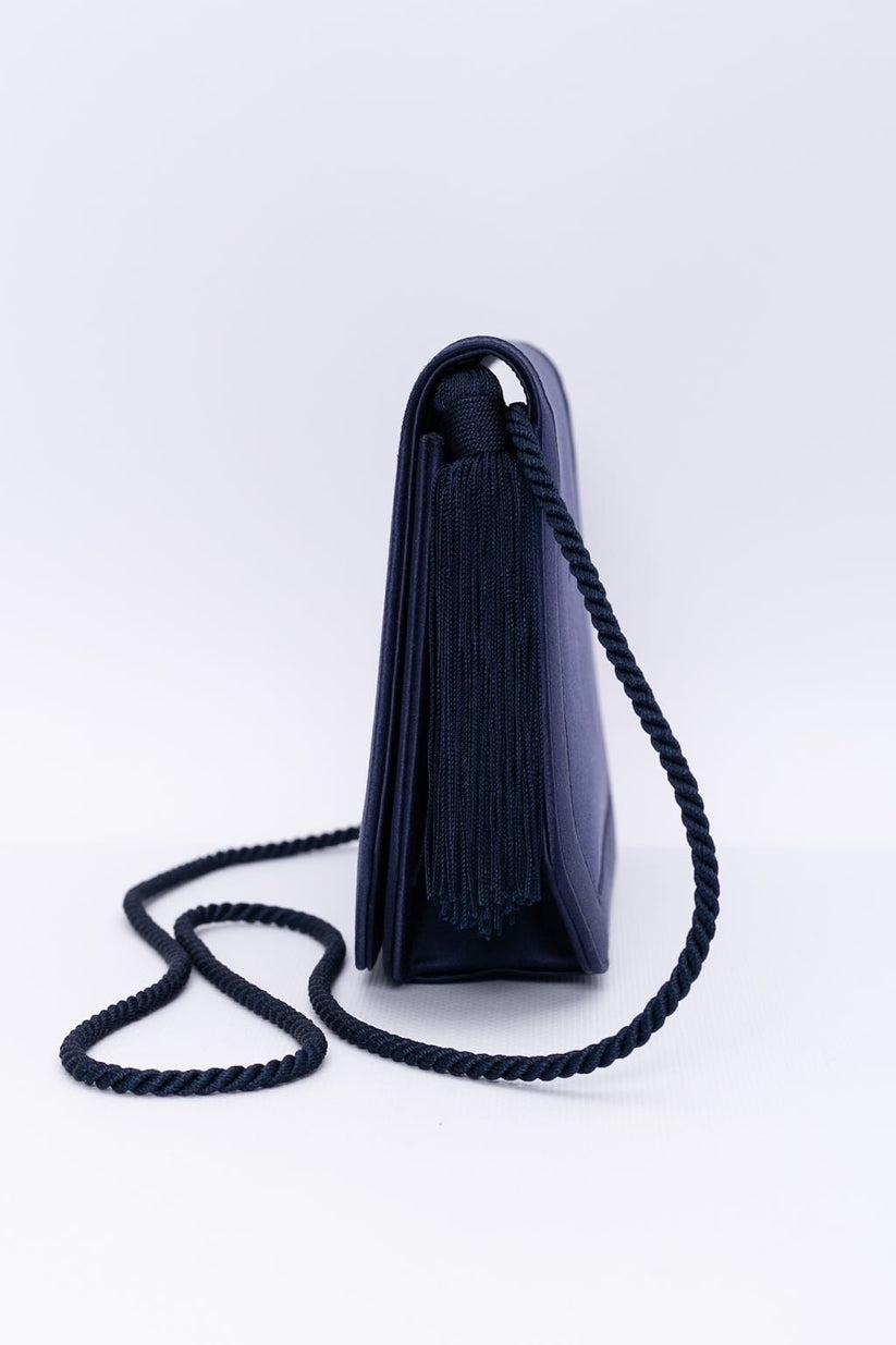 Renaud Pellegrino (Made in France) Evening clutch in dark blue satin embellished with a passementerie tassel. It can be worn as a shoulder bag thanks to its strap.

Additional information: 
Dimensions: Width: 22 cm (8.66