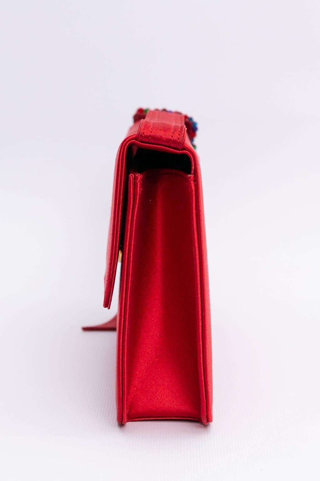 Renaud Pellegrino (hergestellt in Frankreich). Rote Seidentasche mit gürtelähnlichem Griff. Die Schnalle ist mit Glasperlen bestickt. Drei aufgesetzte Taschen, davon eine mit Reißverschluss.

Zusätzliche Informationen: 
Abmessungen: Länge: 25,5 cm