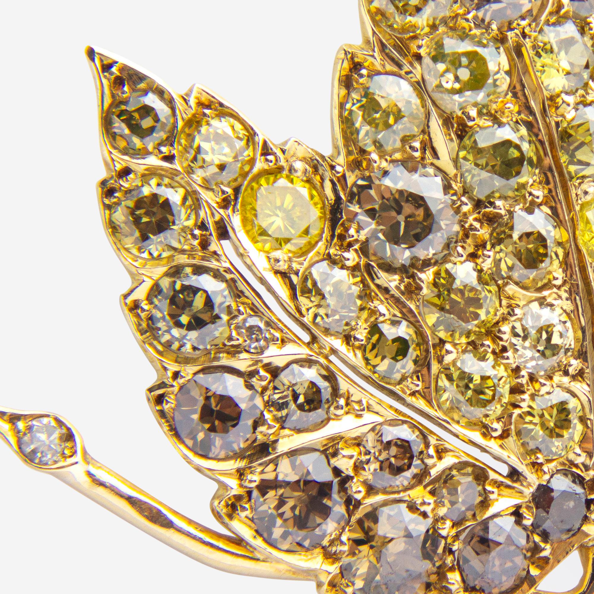 This diamond brooch pin has been crafted in 18-karat yellow gold and set with fancy coloured diamonds, manufactured by Rene Boivin. The piece which dates to the 1950s takes the form of a vine leaf and is set with 57 brilliant cut diamonds ranging