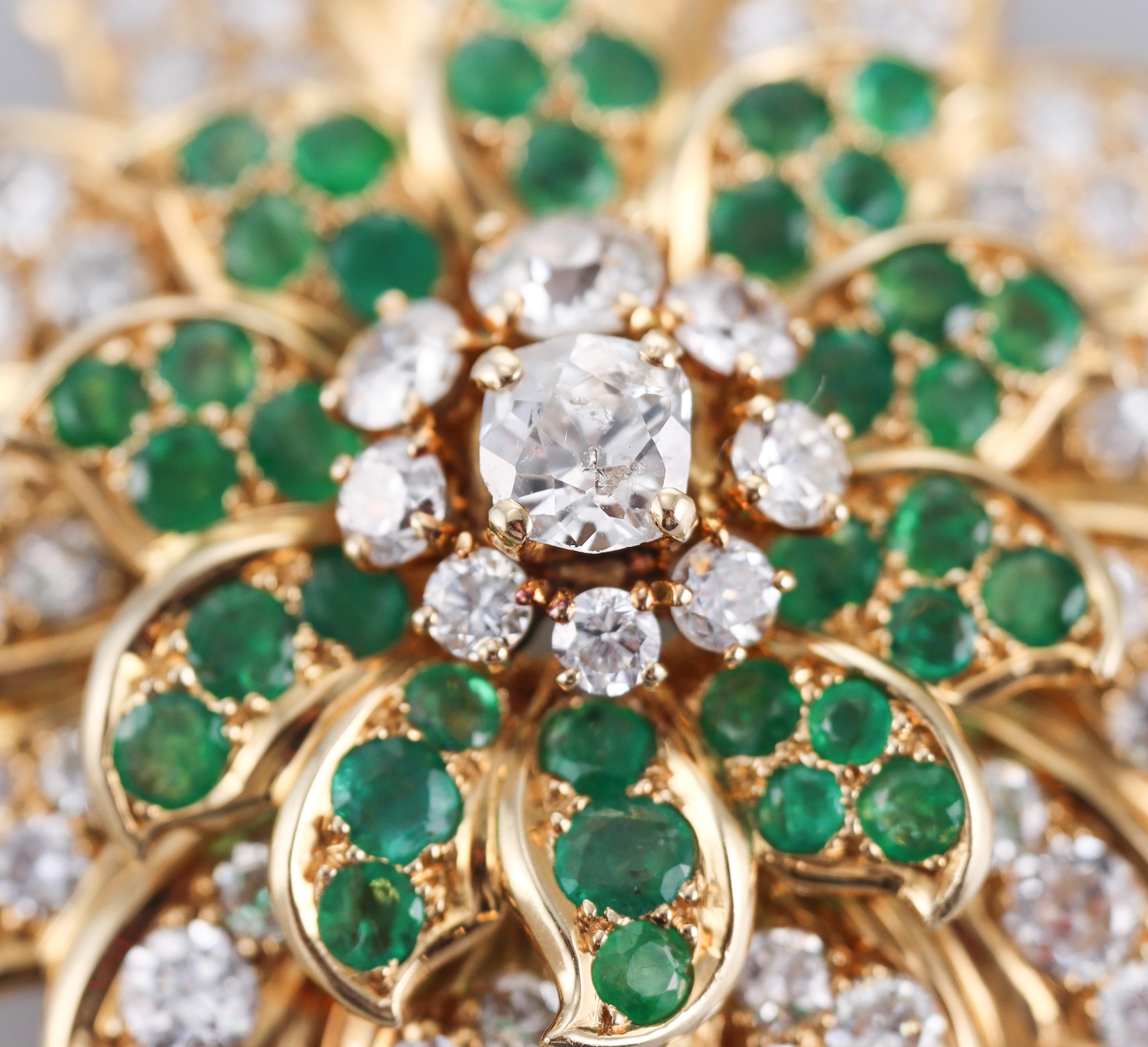 An exquisite 18k yellow gold flower brooch by René Boivin, adorned with vibrant emeralds and a total of approx. 9 carats in FG/VS diamonds.
Brooch measures 2